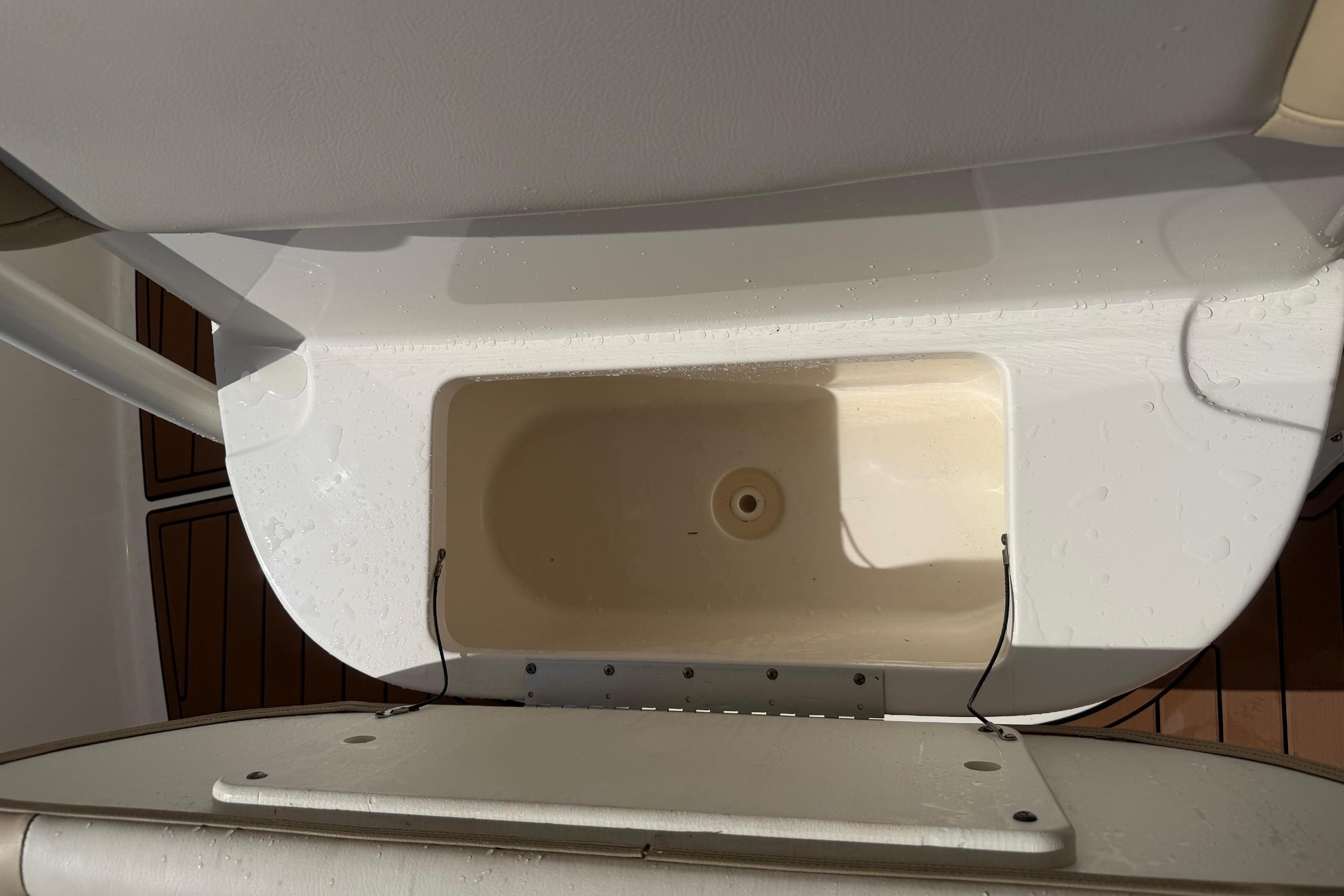 A white boat with a built-in compartment and wooden flooring.