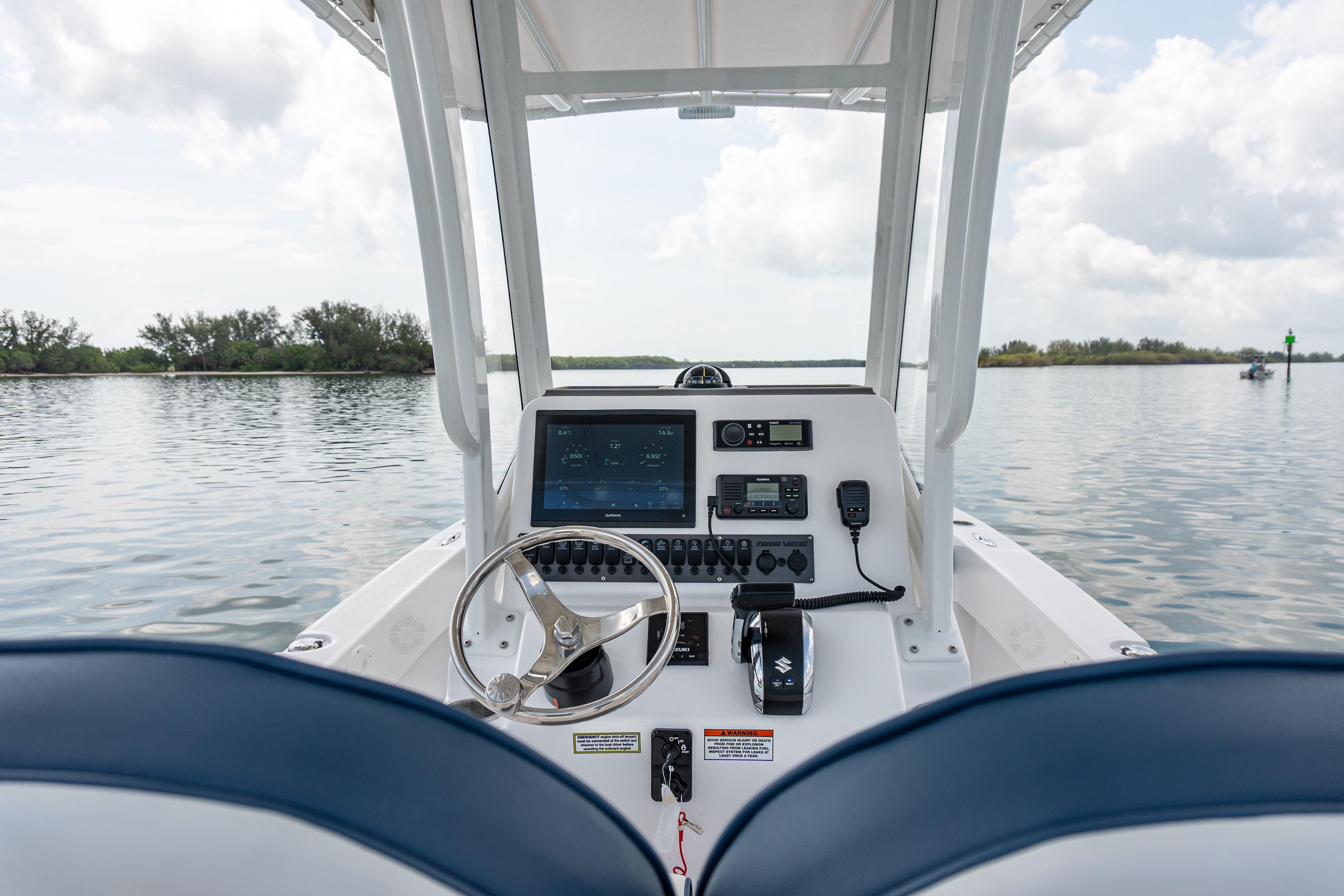 2026 Twin Vee 22 BayCat boat dashboard with steering wheel and navigation controls on calm water.