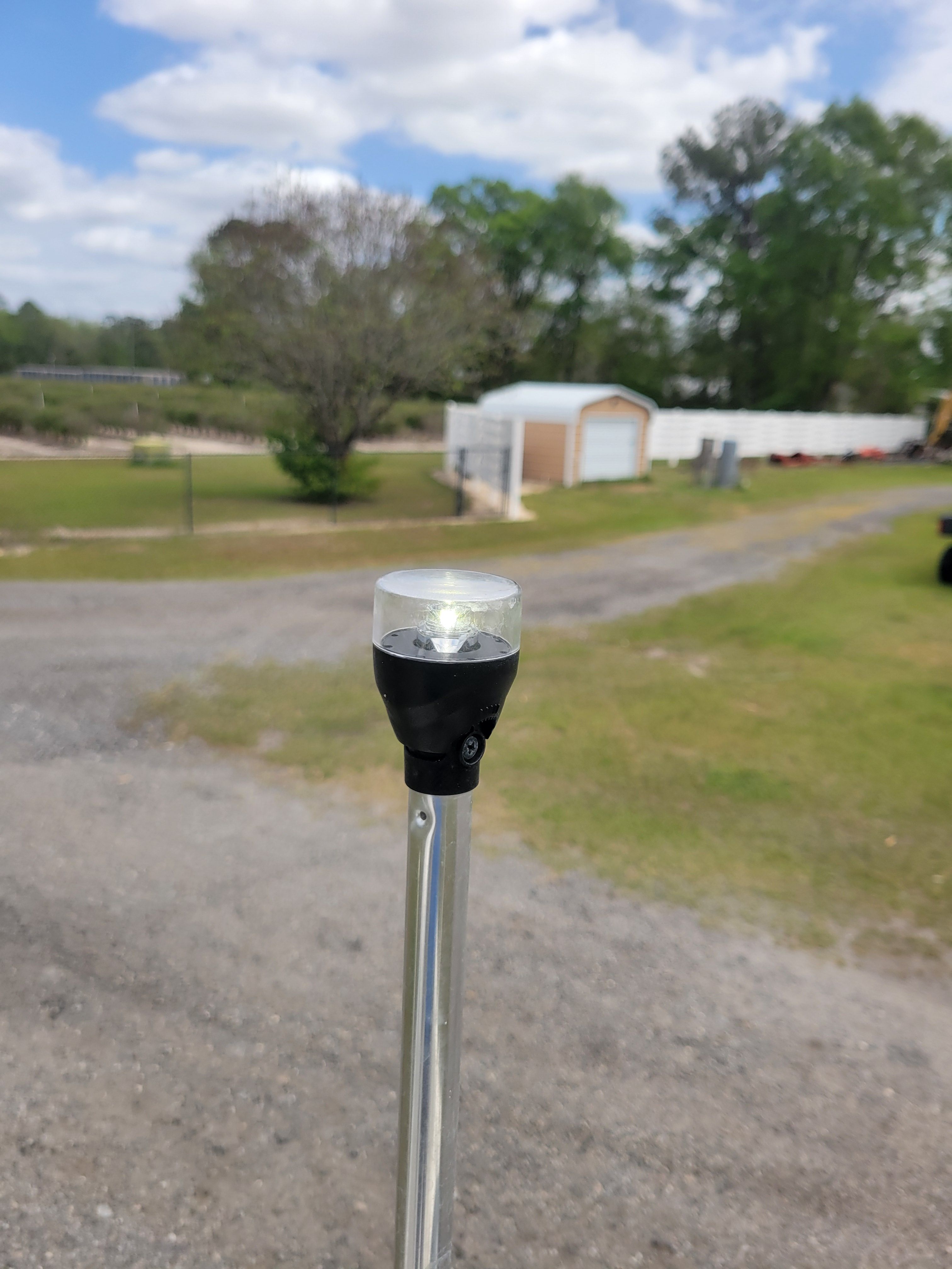 A boat navigation light on a pole, with a rural background and trees.