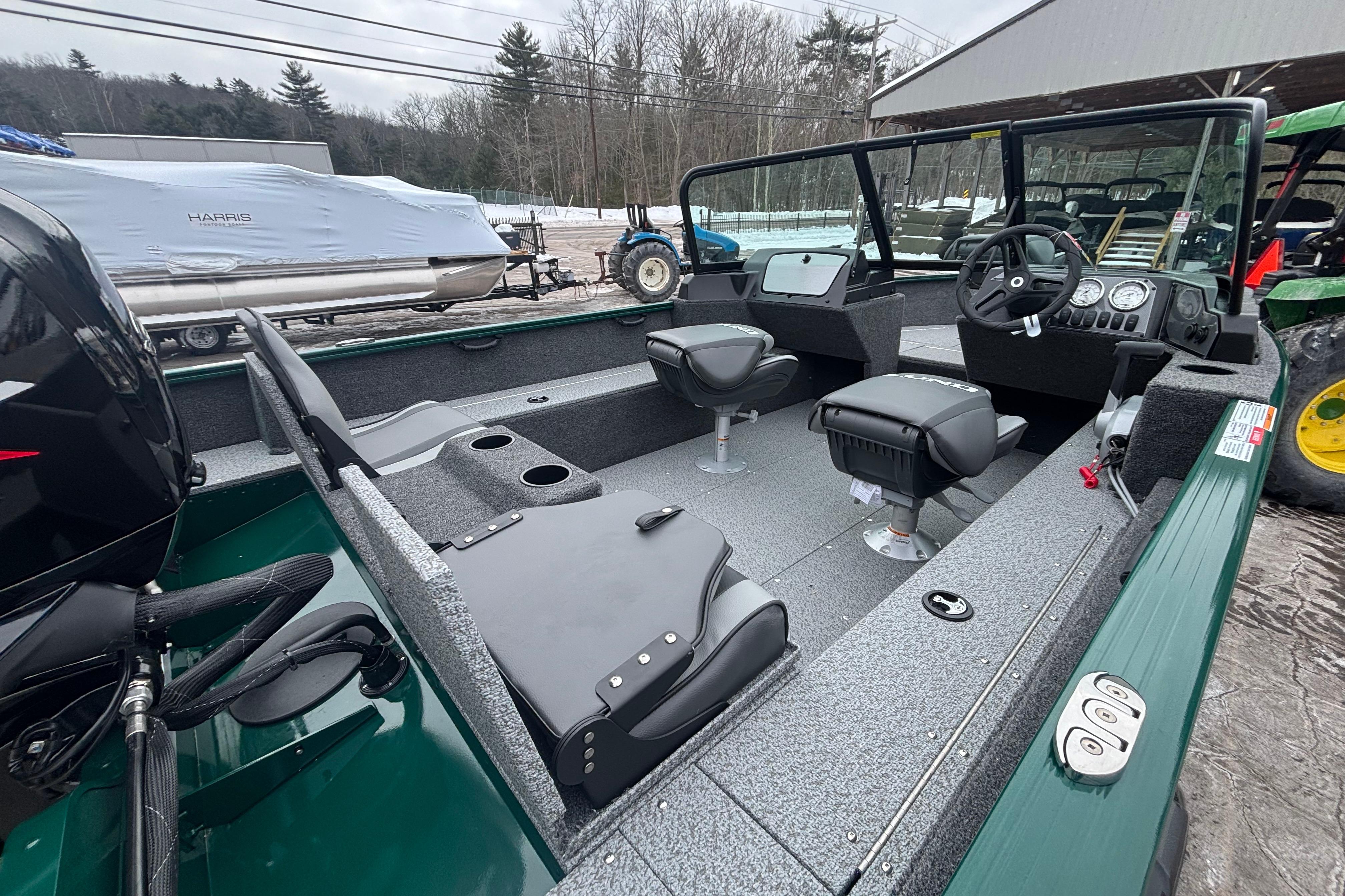2026 Lund 1650 Rebel XL Sport boat interior with seating and controls, parked outdoors.