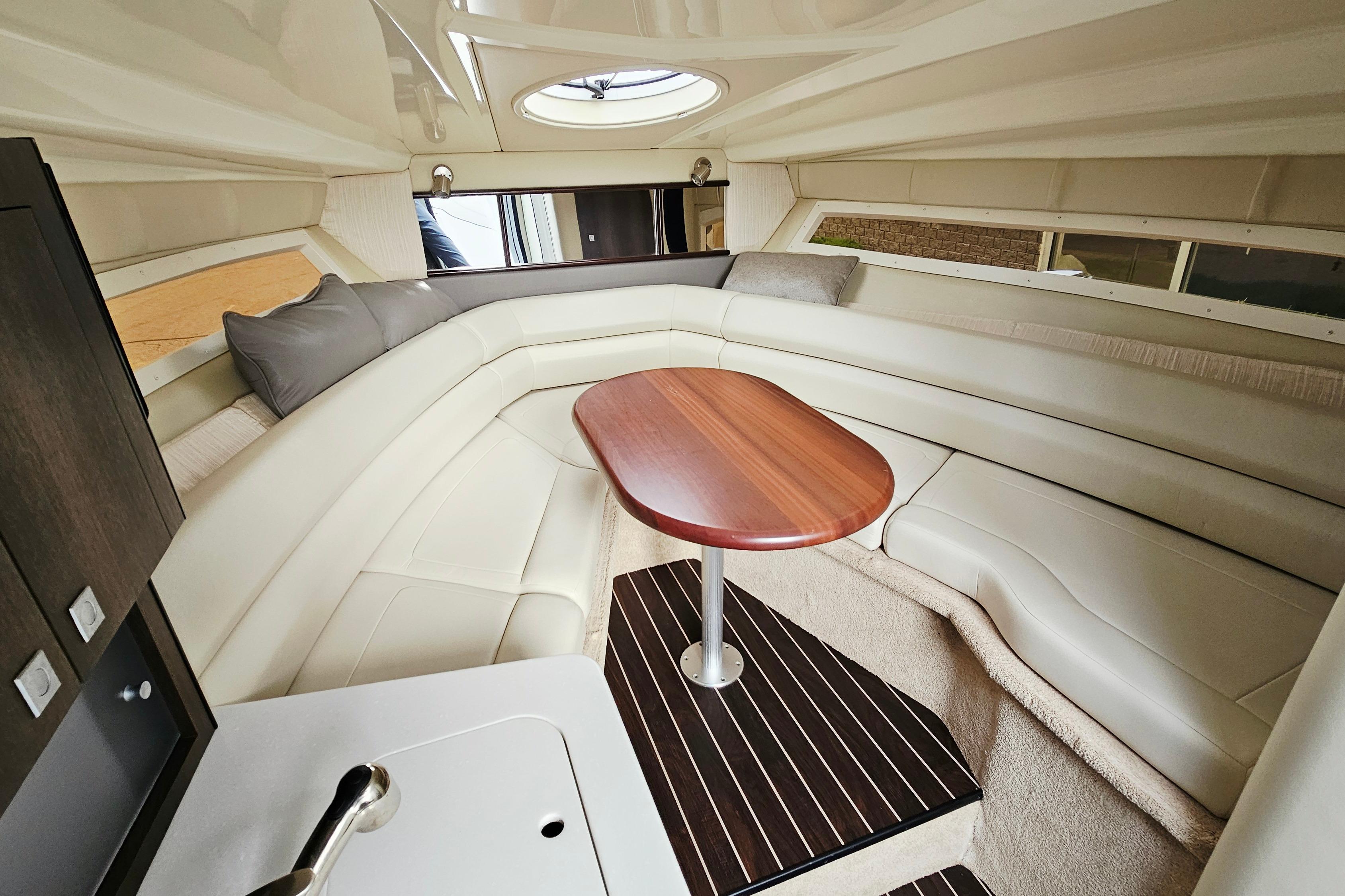 Luxurious interior of 2016 Monterey 295 Sport Yacht with elegant seating and wooden table.