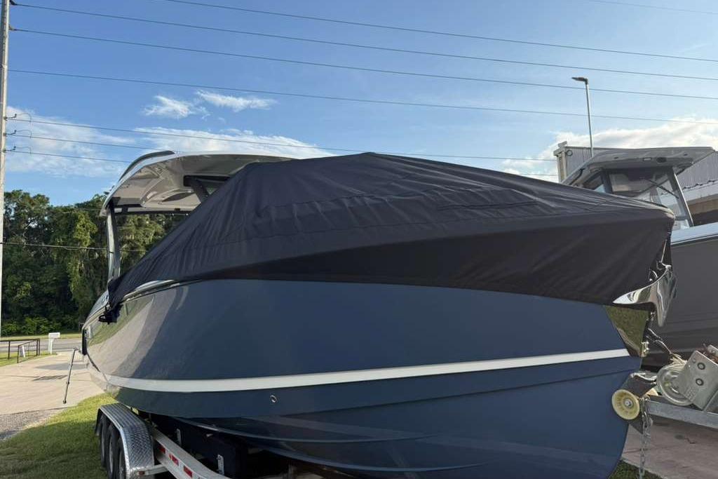 2026 Monterey Elite 30 OB boat with cover on trailer, outdoors.