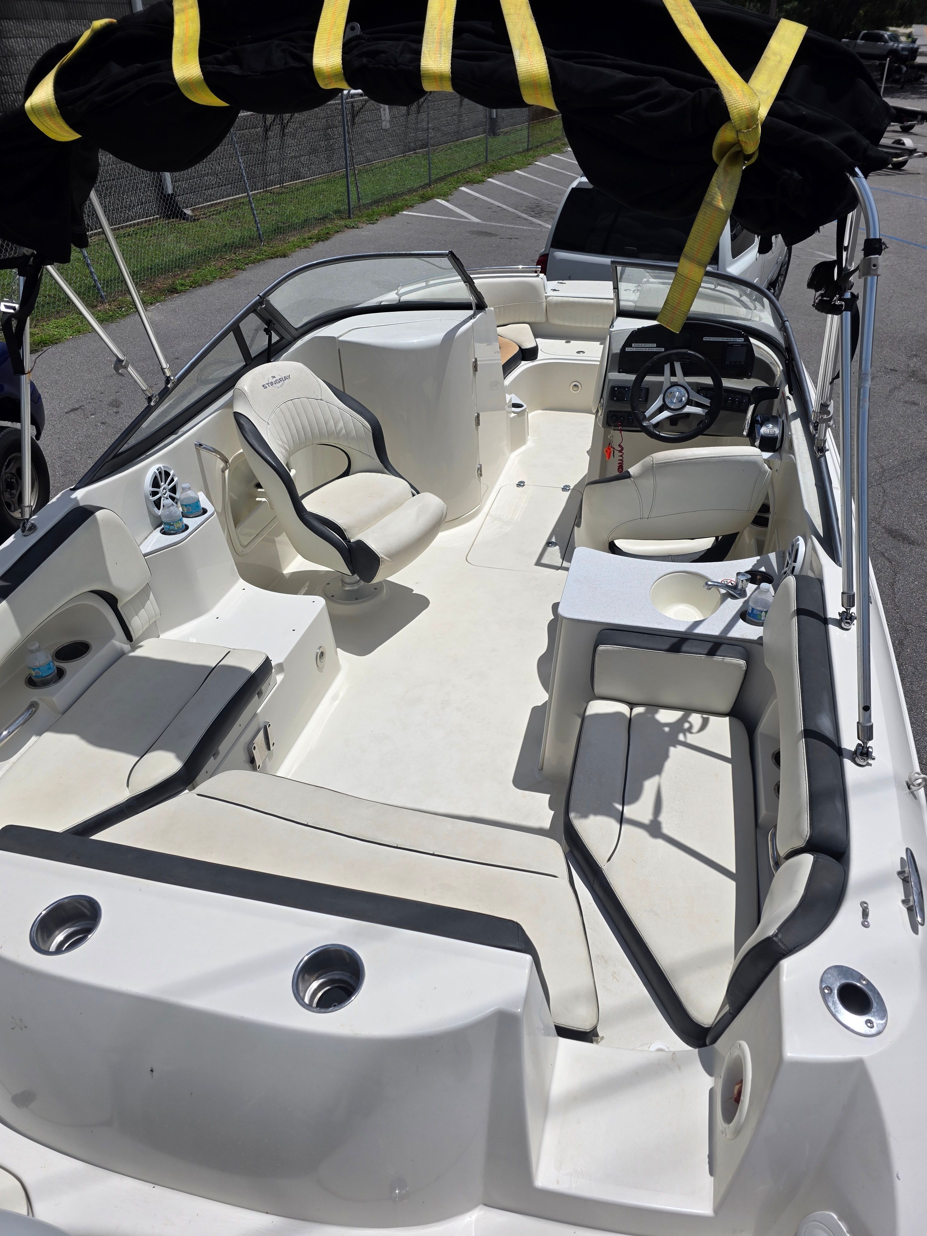 A modern recreational boat with white seating and a black sunshade, parked on a trailer.