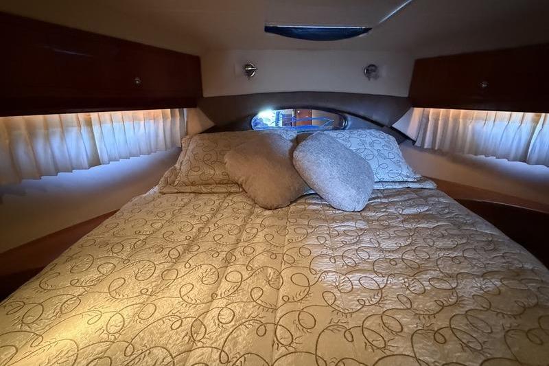 Luxurious cabin interior of 2010 Regal 46 Sport Coupe with elegant bedding and soft lighting.