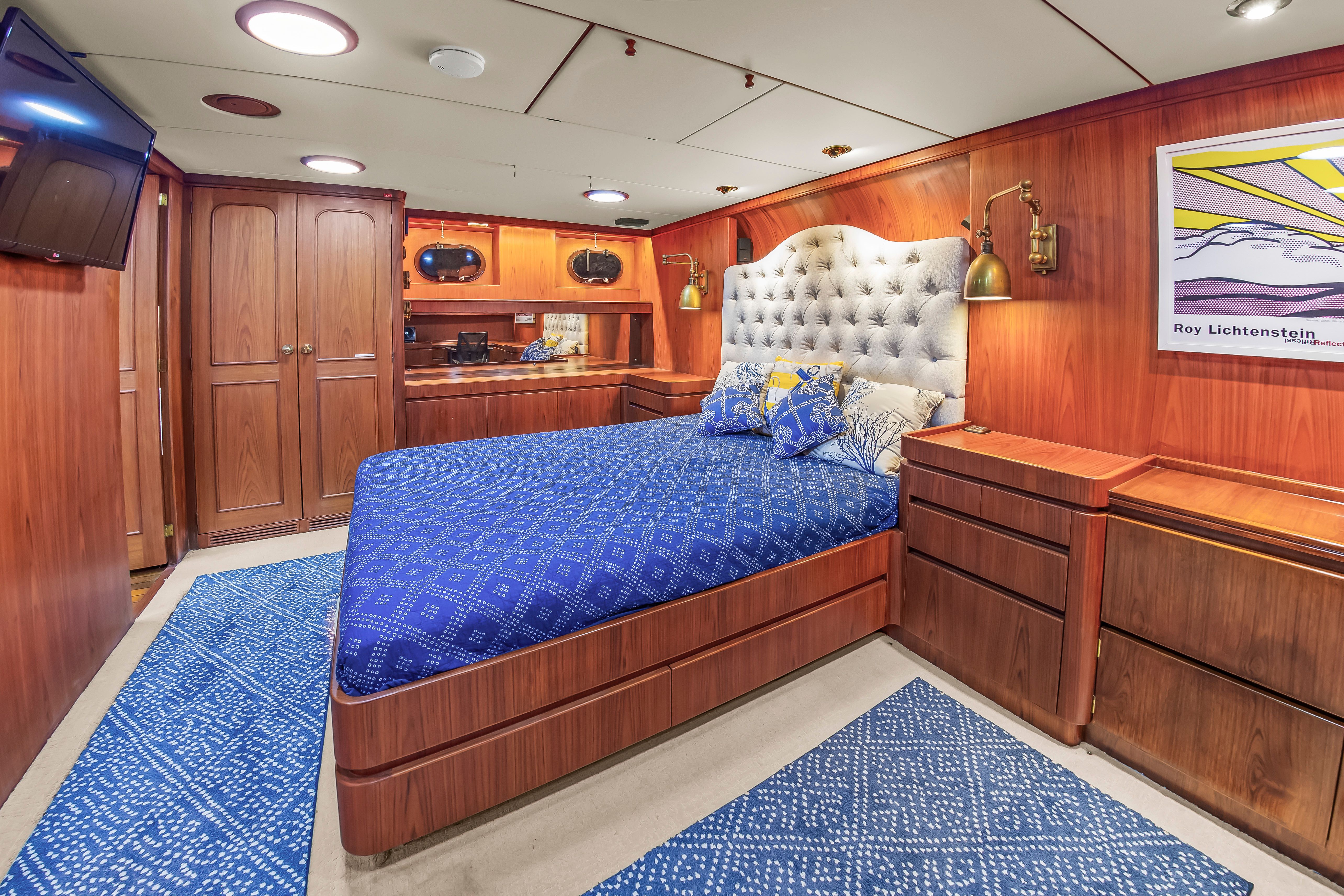 Luxurious cabin with a large bed, wooden furnishings, and blue accents on a yacht.