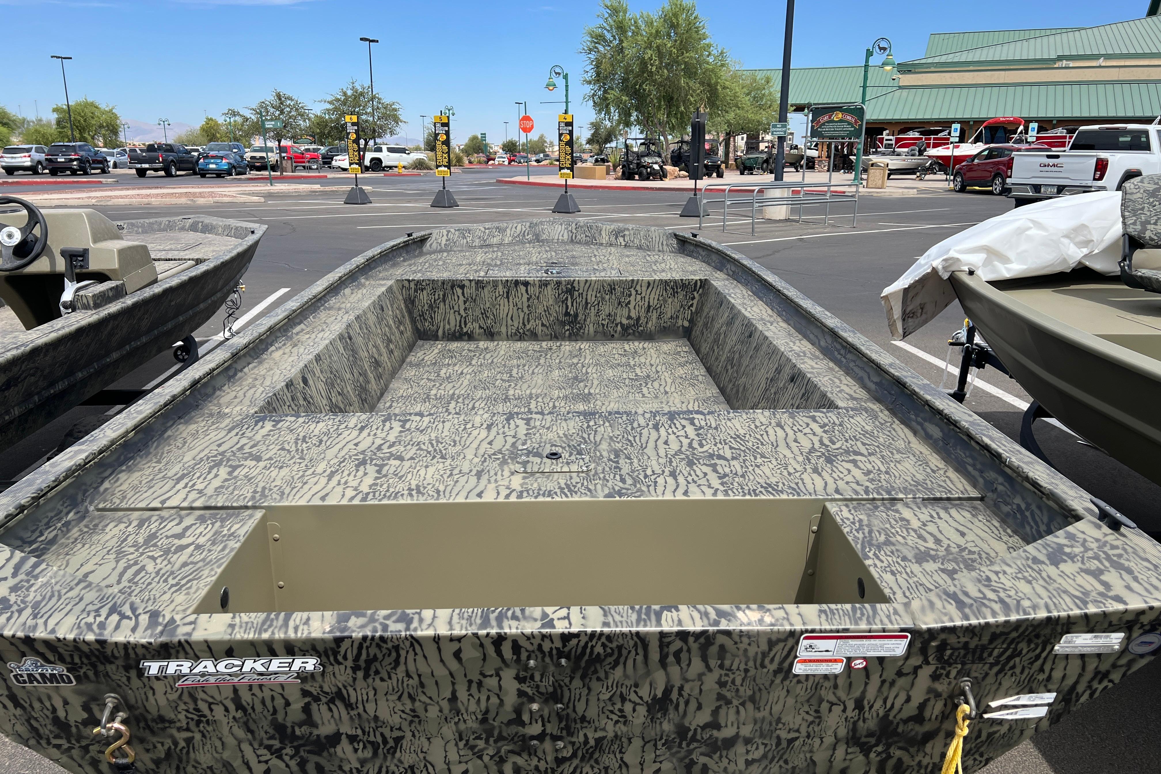 2026 Tracker Grizzly 1754 Utility boat in a parking lot, showcasing camouflage design.