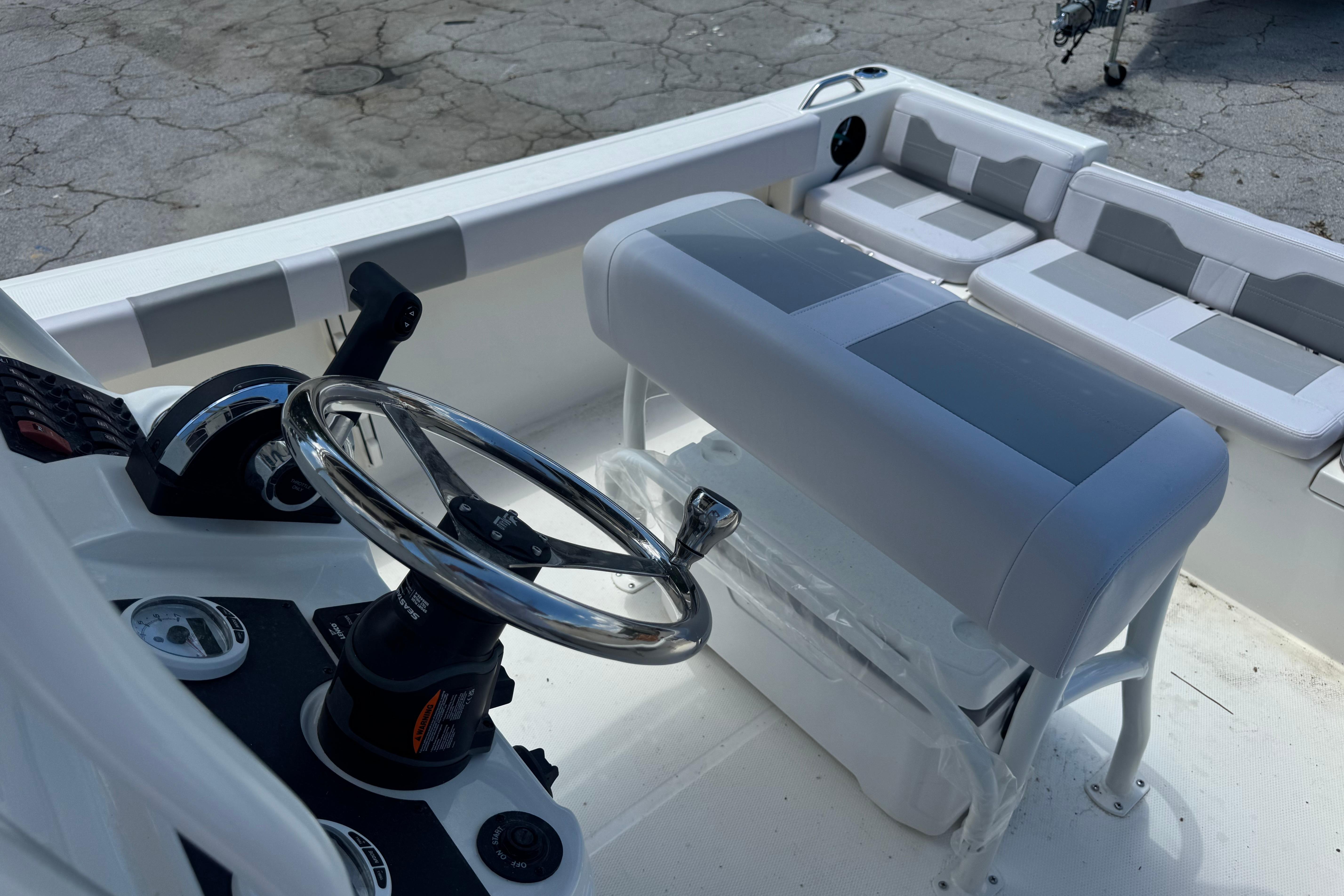 Interior view of a 2026 Mako 214 Center Console boat with steering wheel and seating.