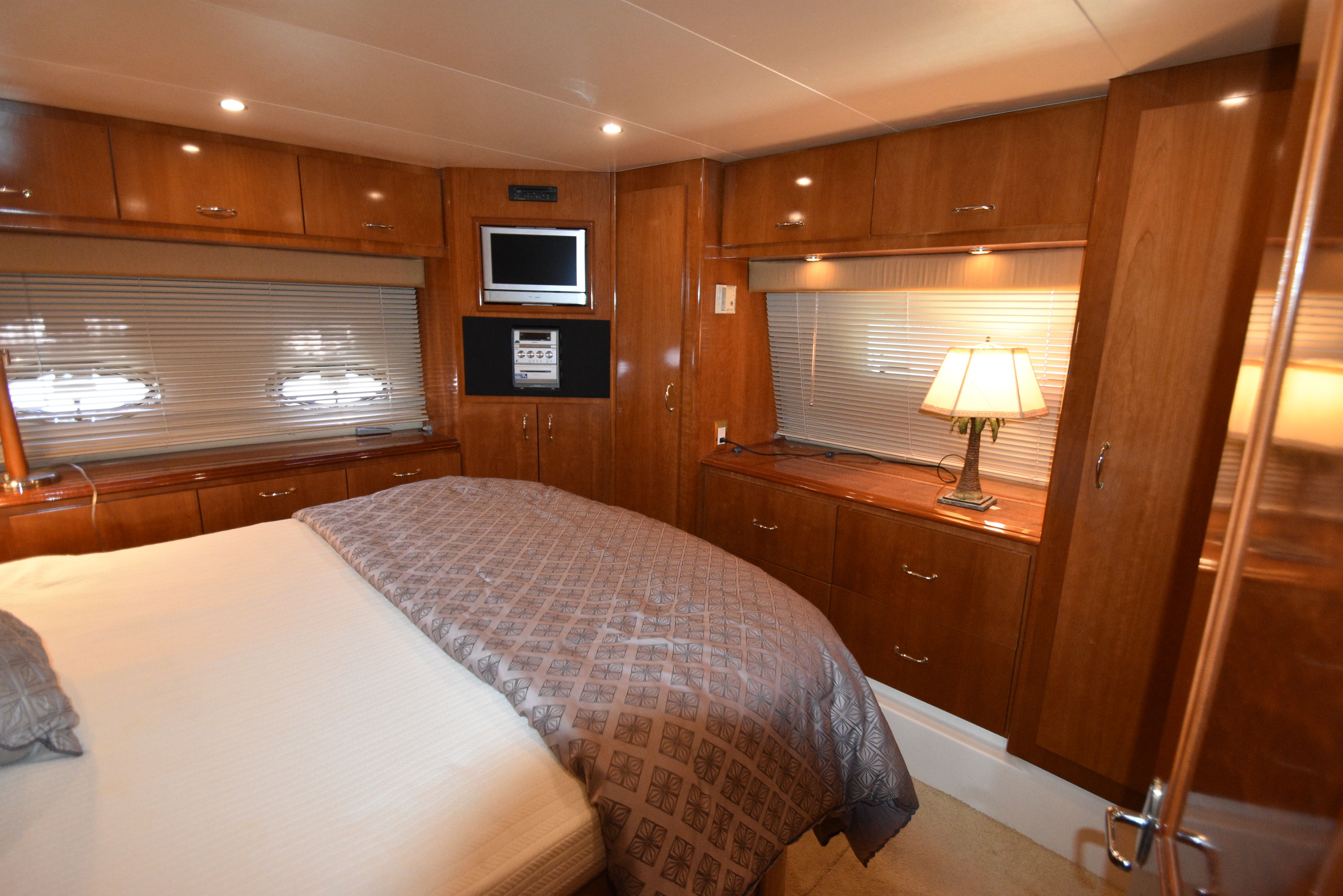 Interior of a luxurious yacht with wooden cabinetry, a bed, and a television.