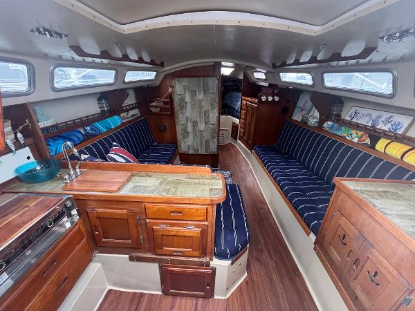 Interior of a 1980 Catalina 30 sailboat with wood cabinetry and striped seating.