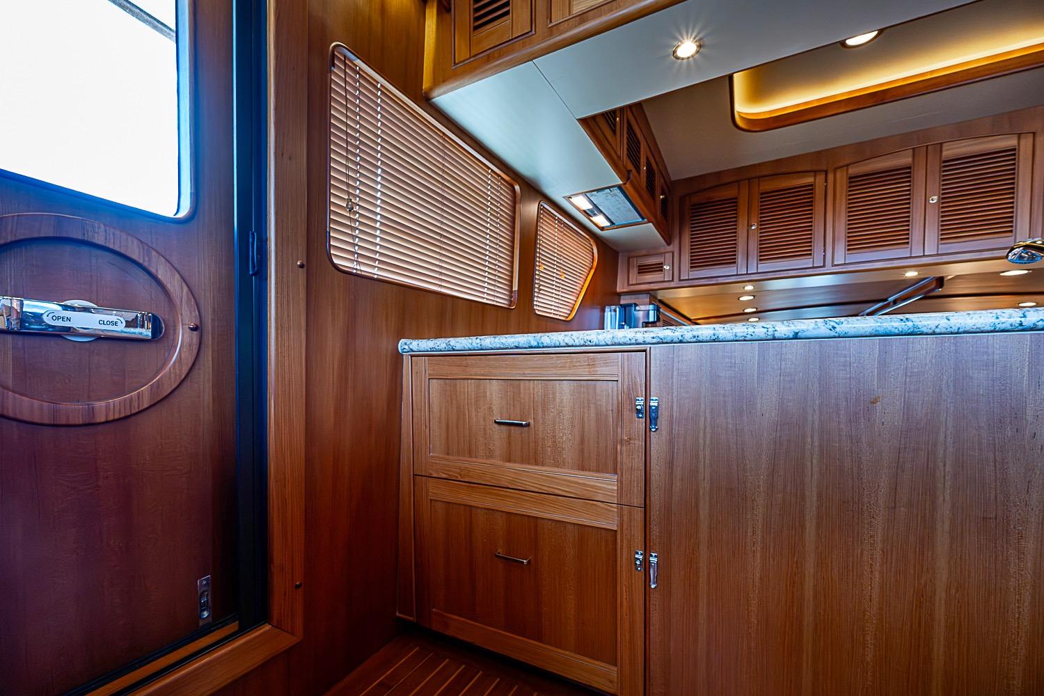 Luxurious wooden interior of 2014 Marlow 80 Explorer yacht kitchen with granite countertop.