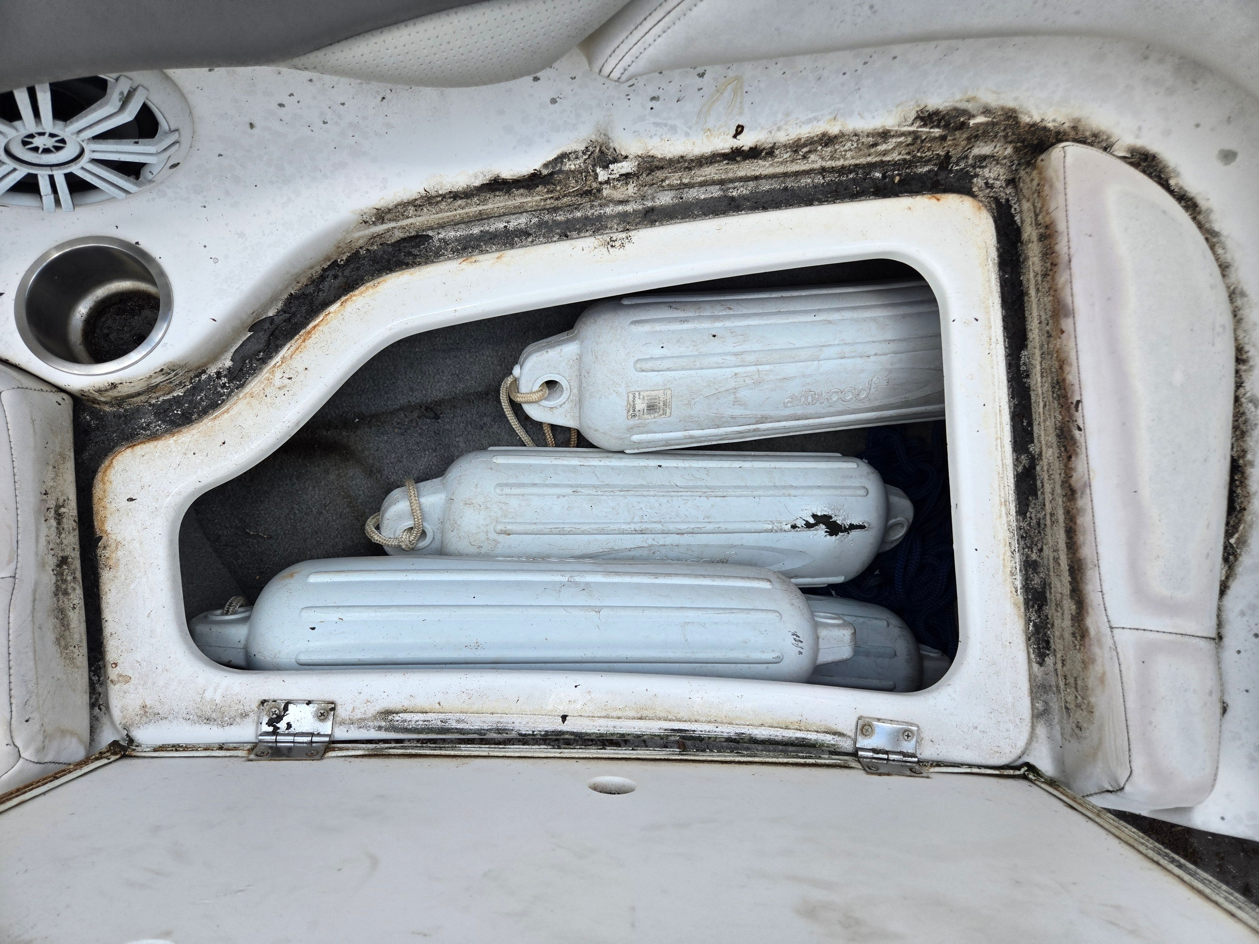 A storage compartment on a boat with several white fenders and a speaker.