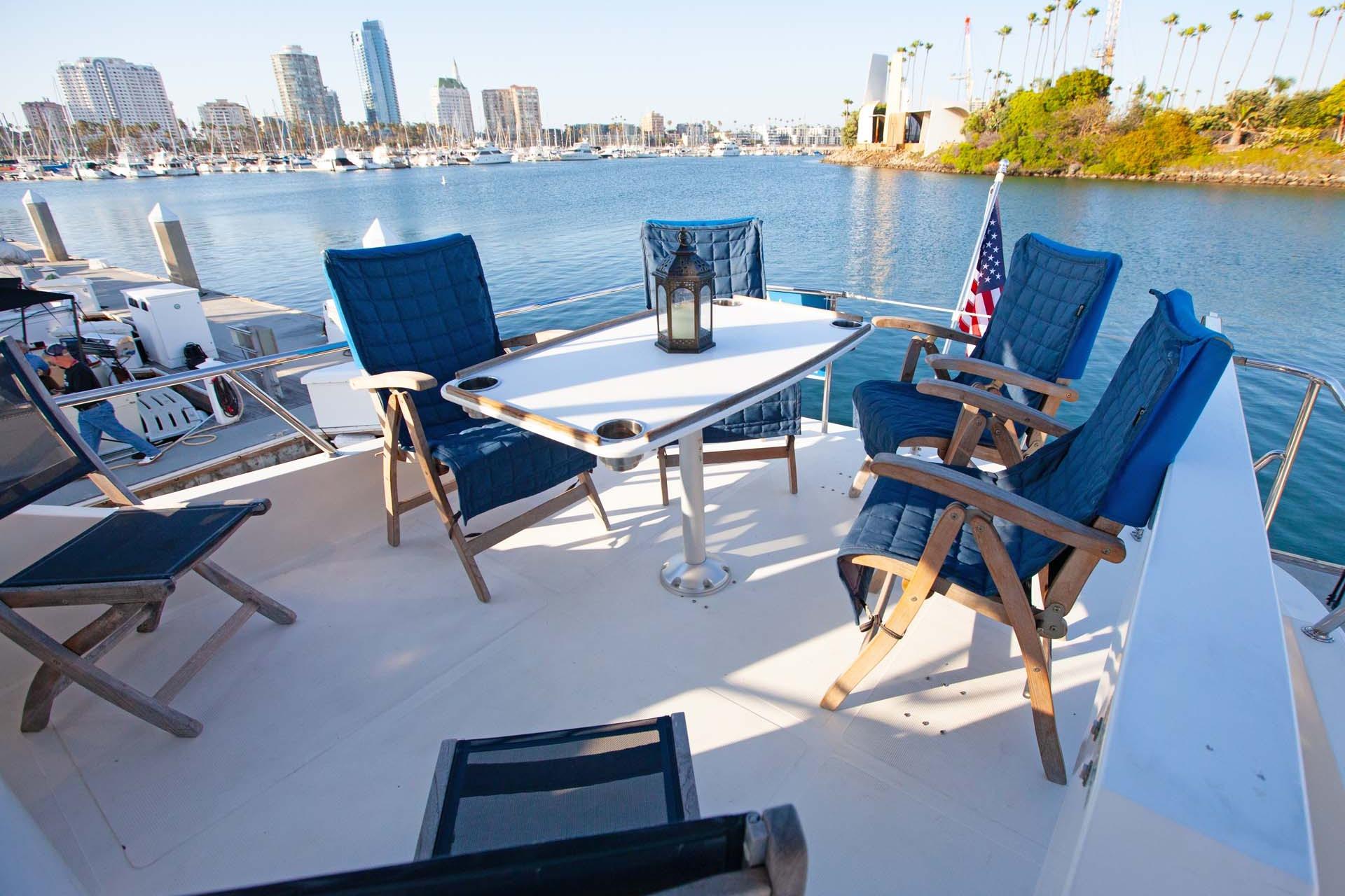 Deck of 1997 McKinna 48' Pilot House yacht with chairs and table, overlooking marina.