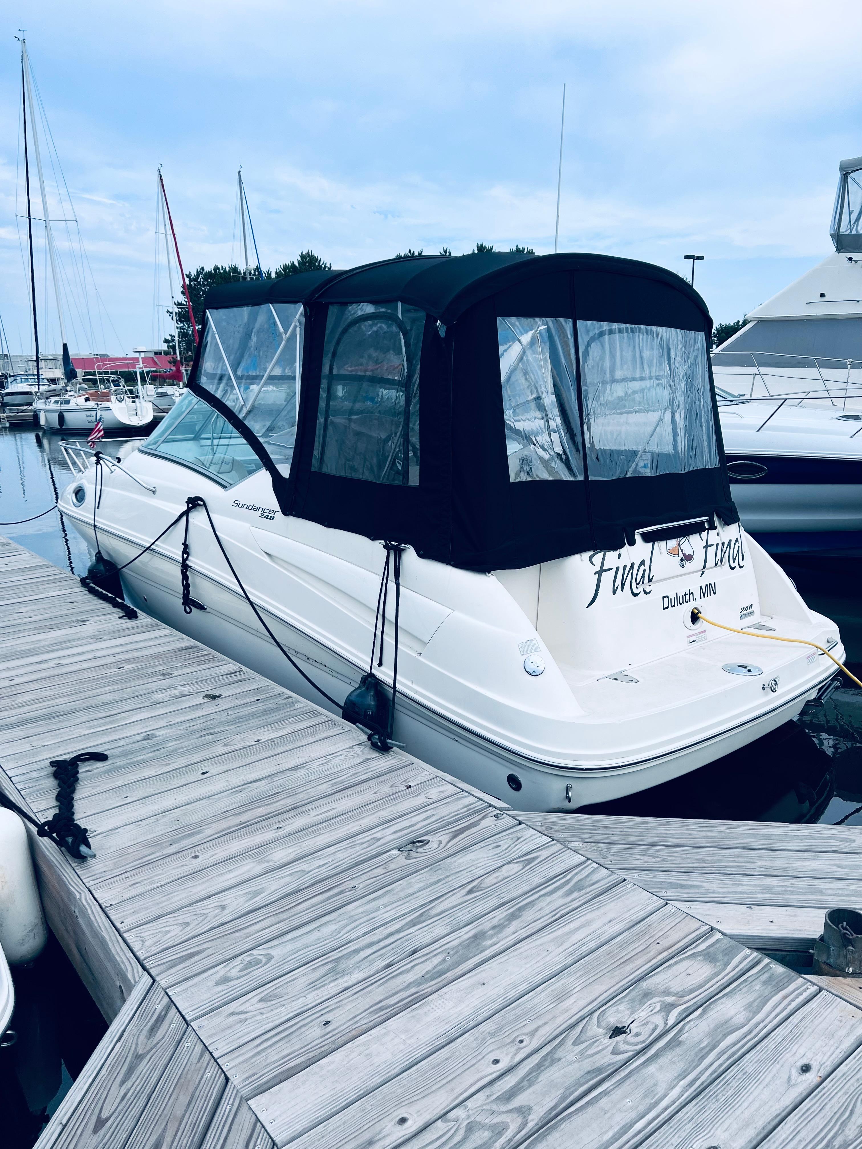 2012 Sea Ray 240 Sundancer docked at marina, covered with black canopy.