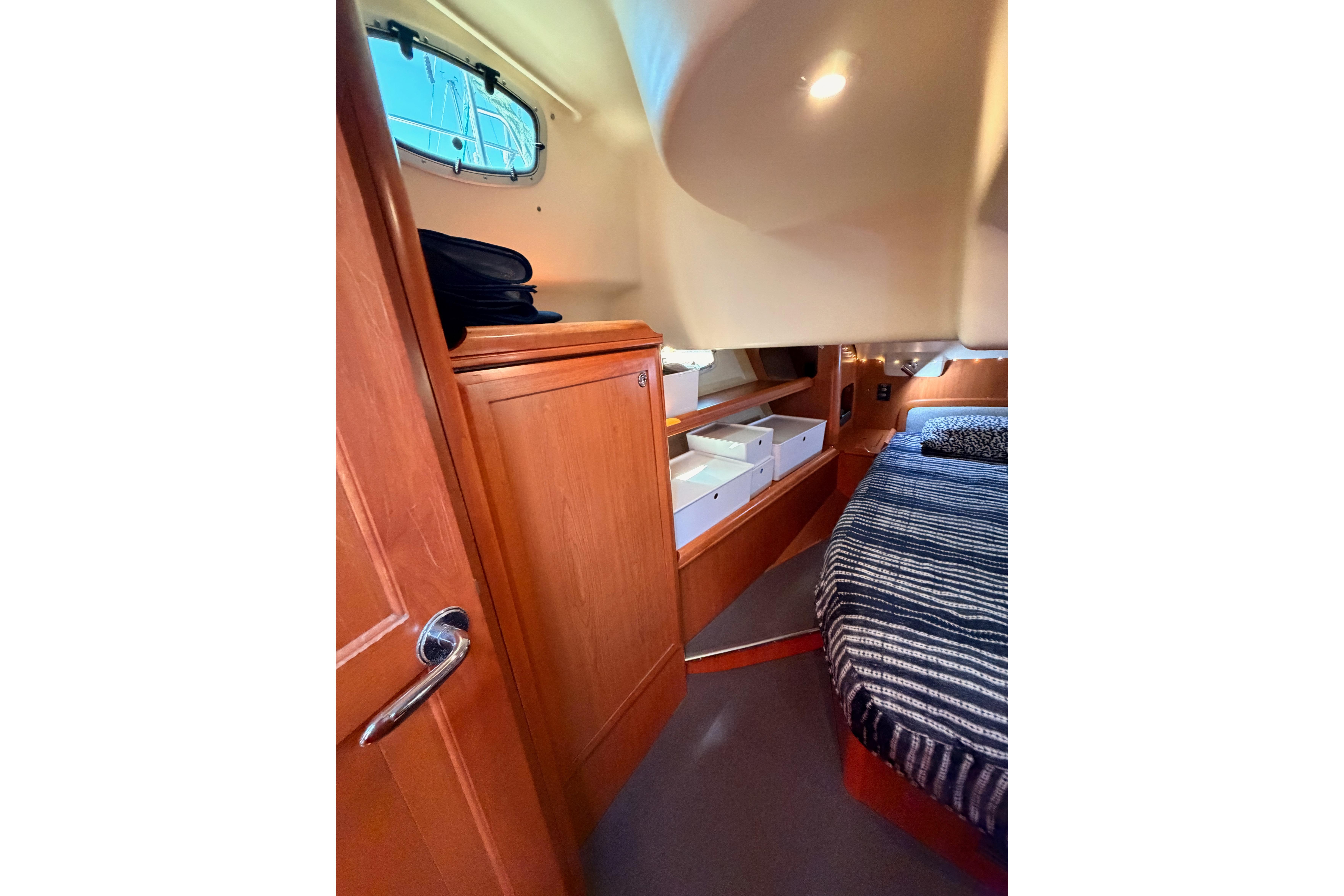 Interior cabin of 2008 Hunter 45 Deck Salon with wood cabinetry and striped bedding.