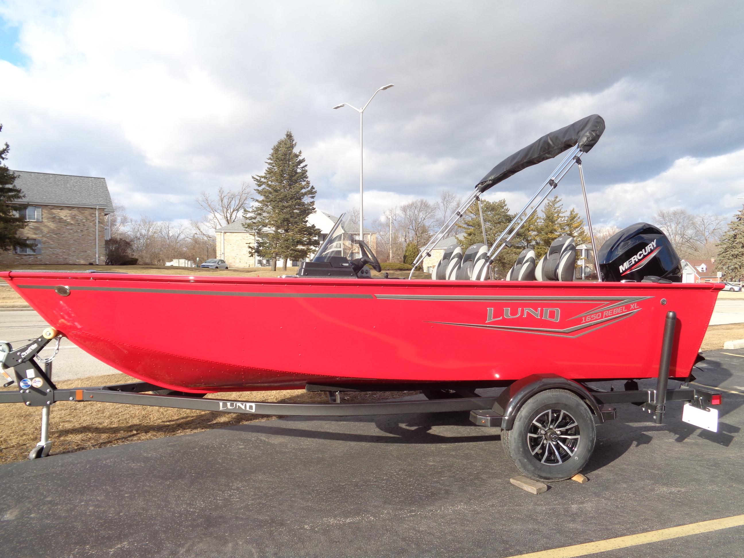 2025 Lund 1650 Rebel XL SS boat in vibrant red on a trailer, parked outdoors.