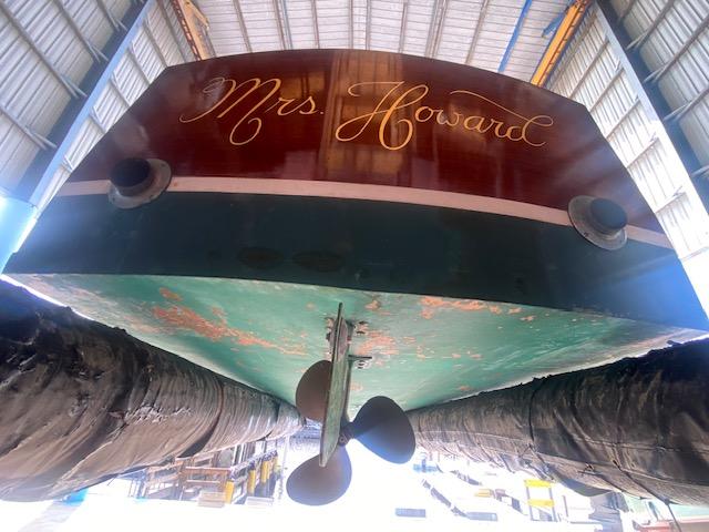 Grand Craft Classic Runabout 2000, named "Mrs. Howard," in a boatyard, viewed from below.