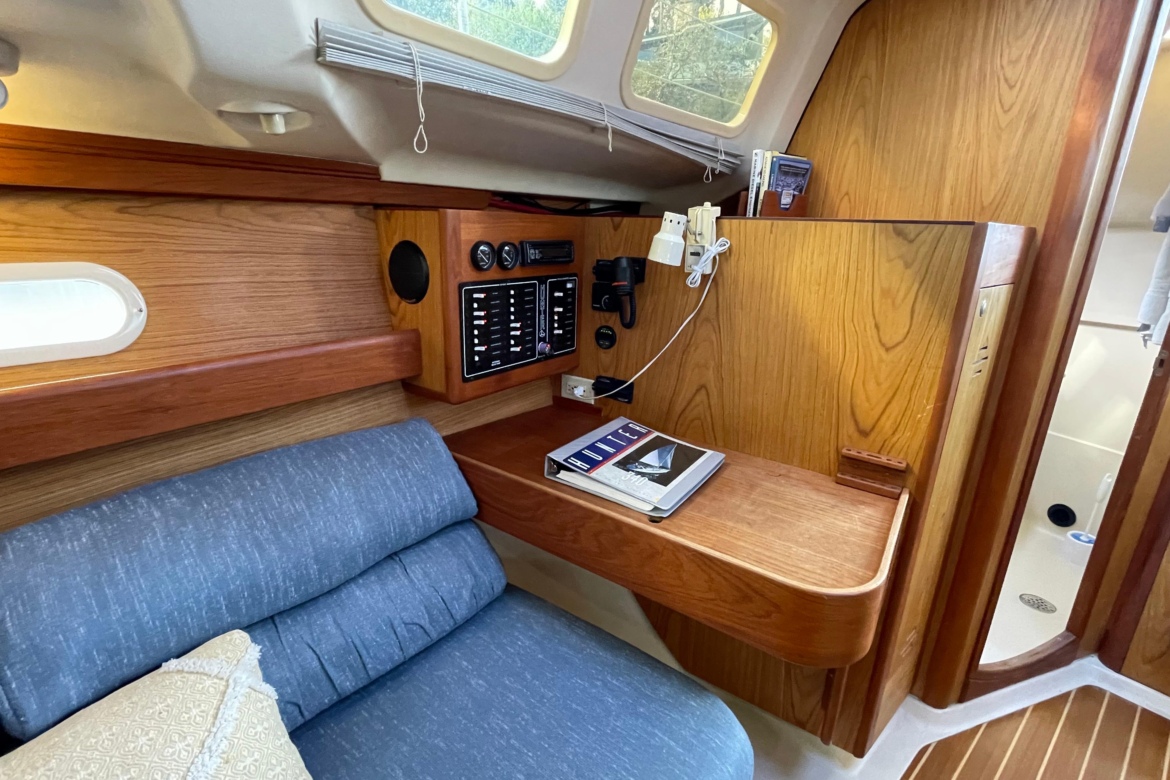 Cozy interior of a 2000 Hunter 340 sailboat with wood paneling and navigation station.