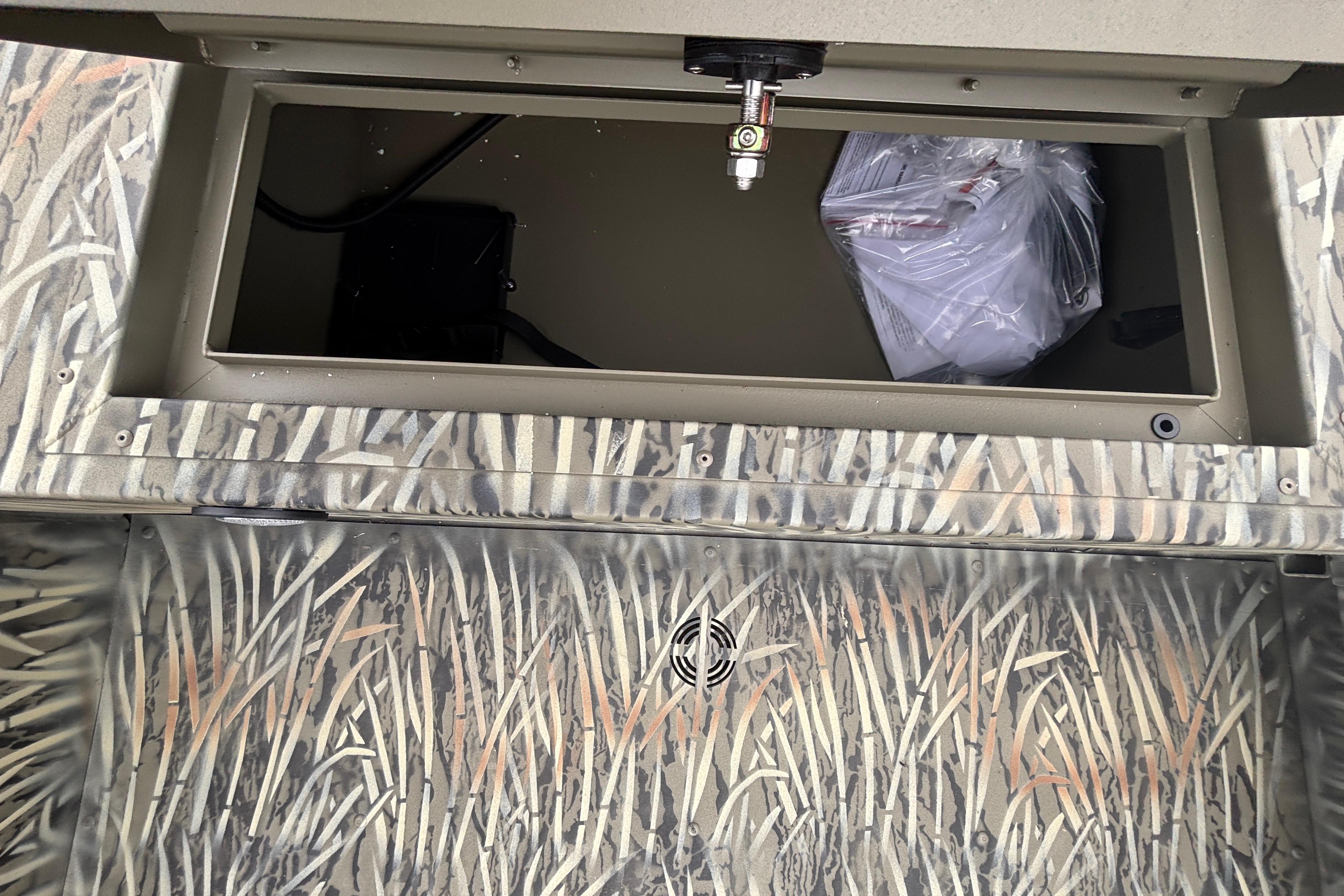 Camouflage interior of 2026 Tracker Grizzly 1654 T Sportsman boat with storage compartment.