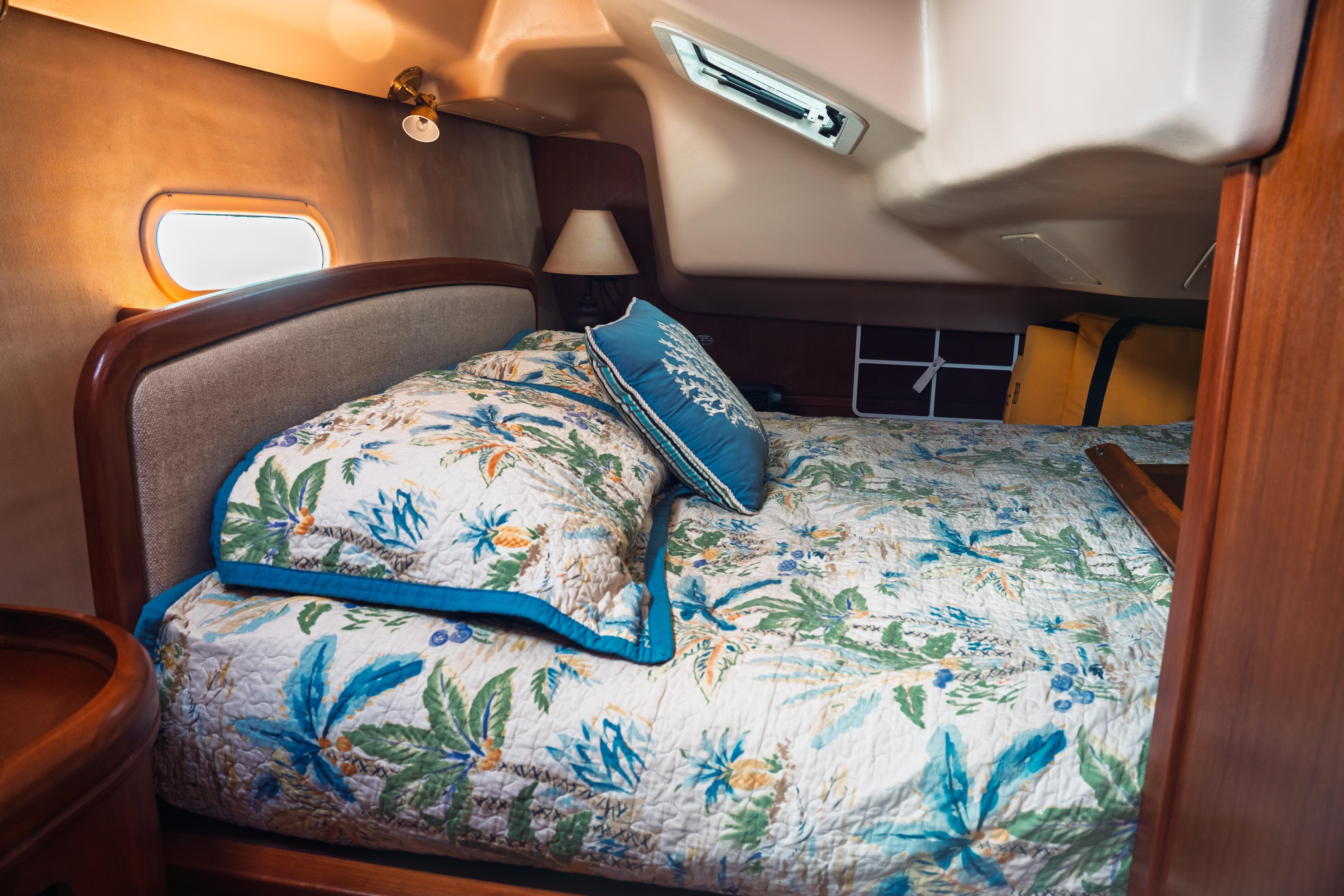 Cozy cabin interior of 2003 Hunter 356 yacht with floral bedding and soft lighting.