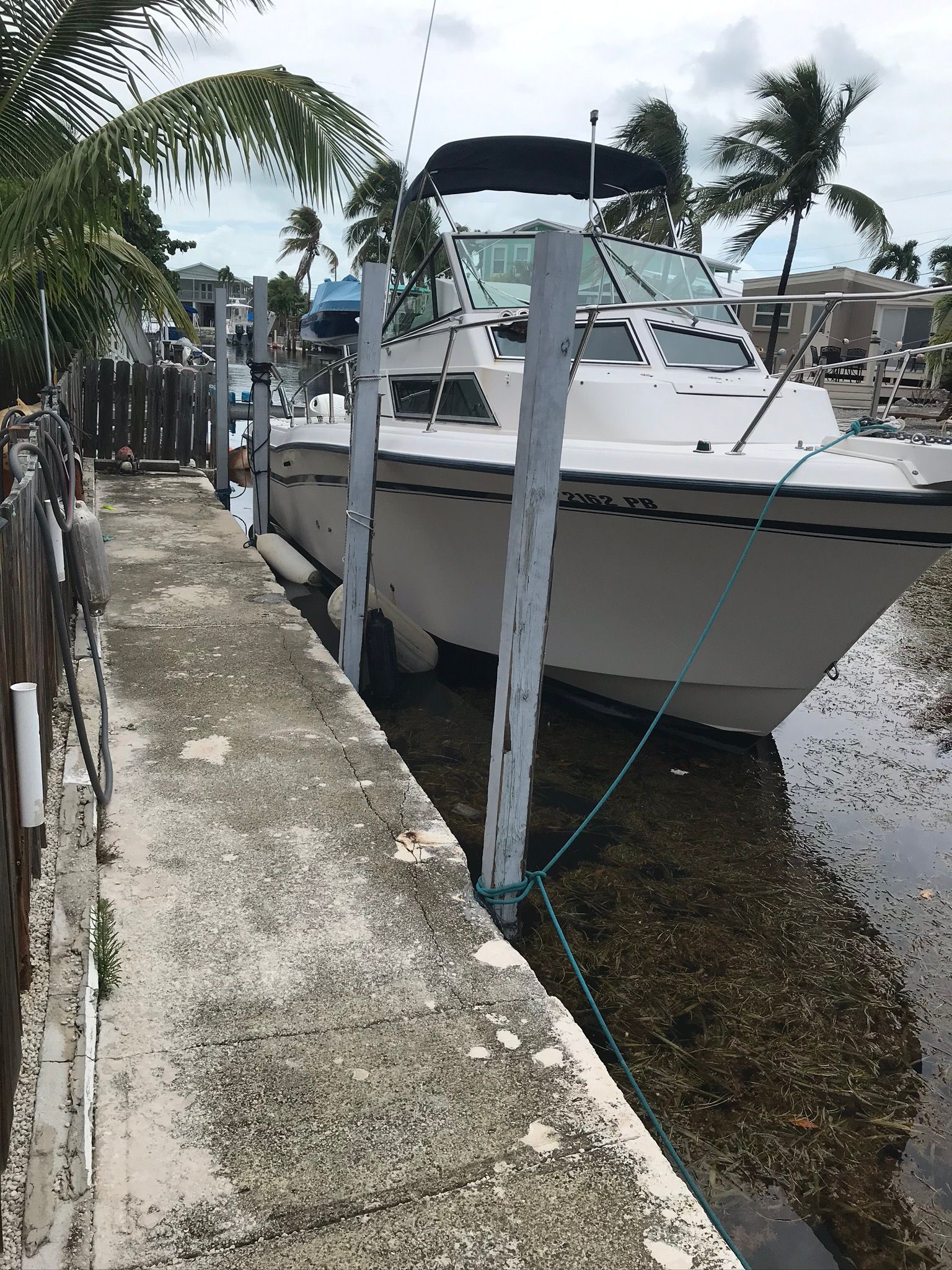 A 1990 Grady-White Sailfish is docked in a tropical canal setting.