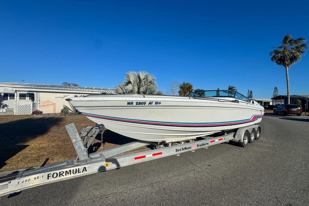 1989 Formula 292 SR-1 boat on trailer, parked in residential area under clear blue sky.