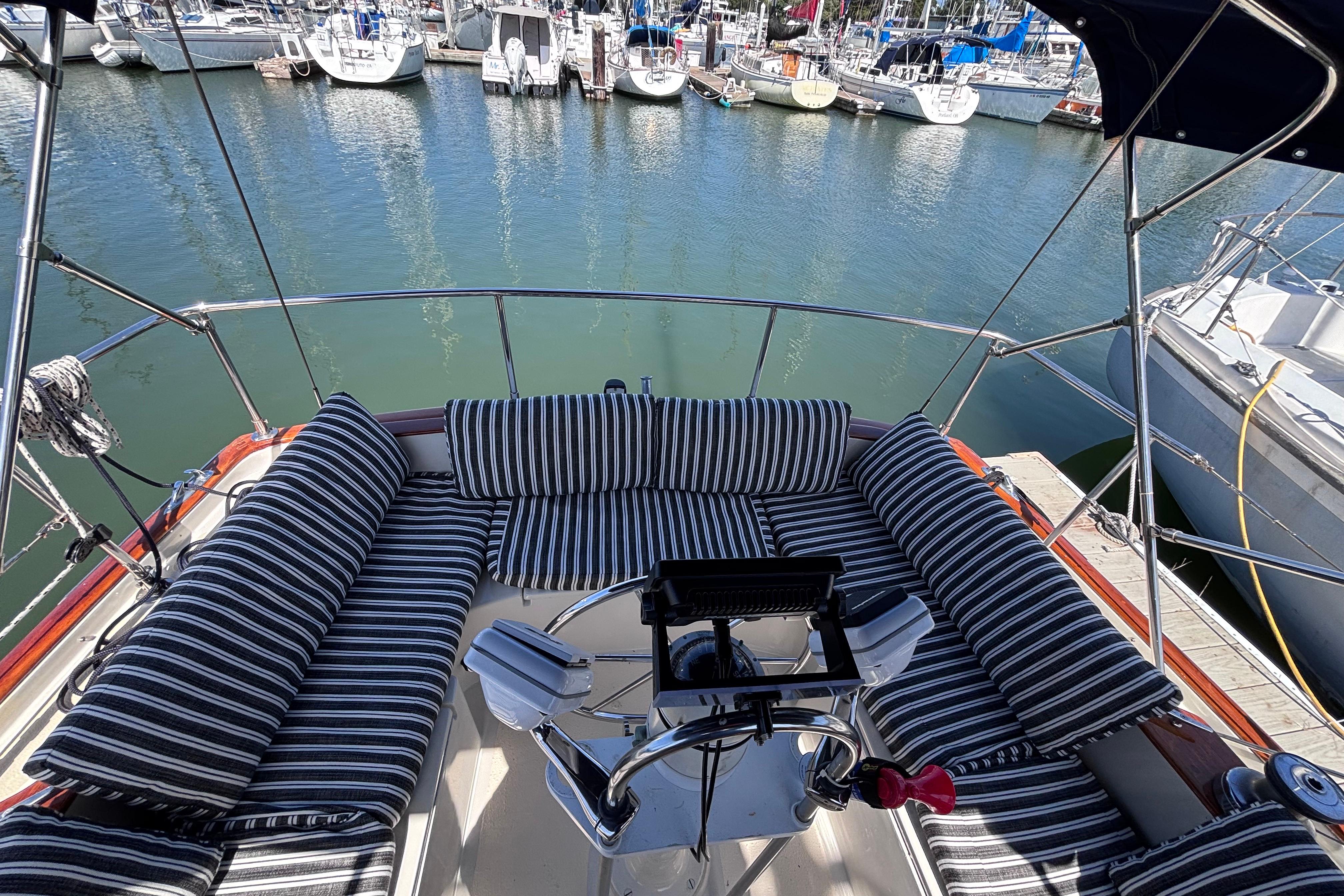 Cockpit of 1978 Swift 33 sailboat with striped cushions, docked in marina.