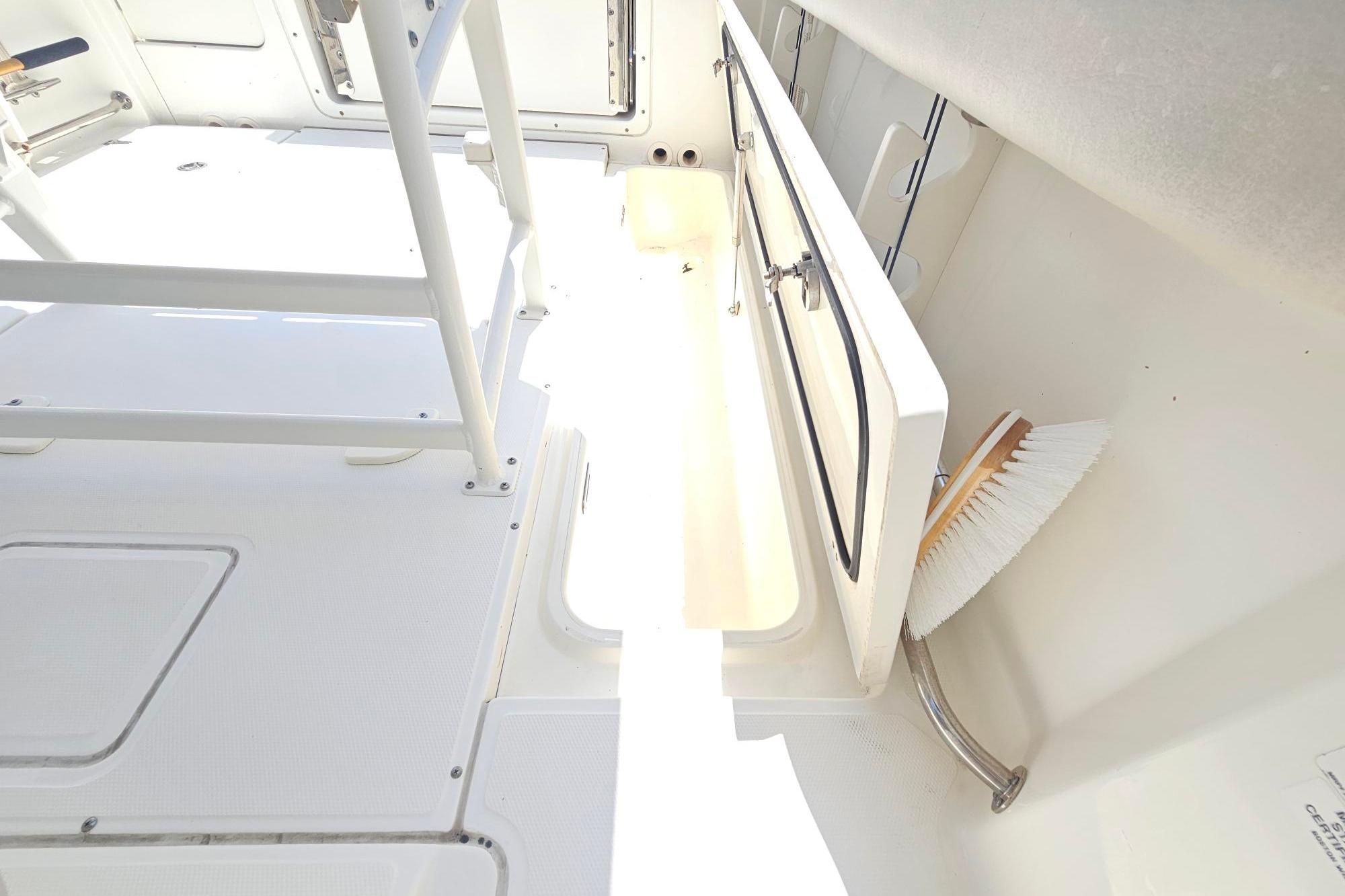 2017 Boston Whaler 230 Outrage interior with storage compartment and cleaning brush.