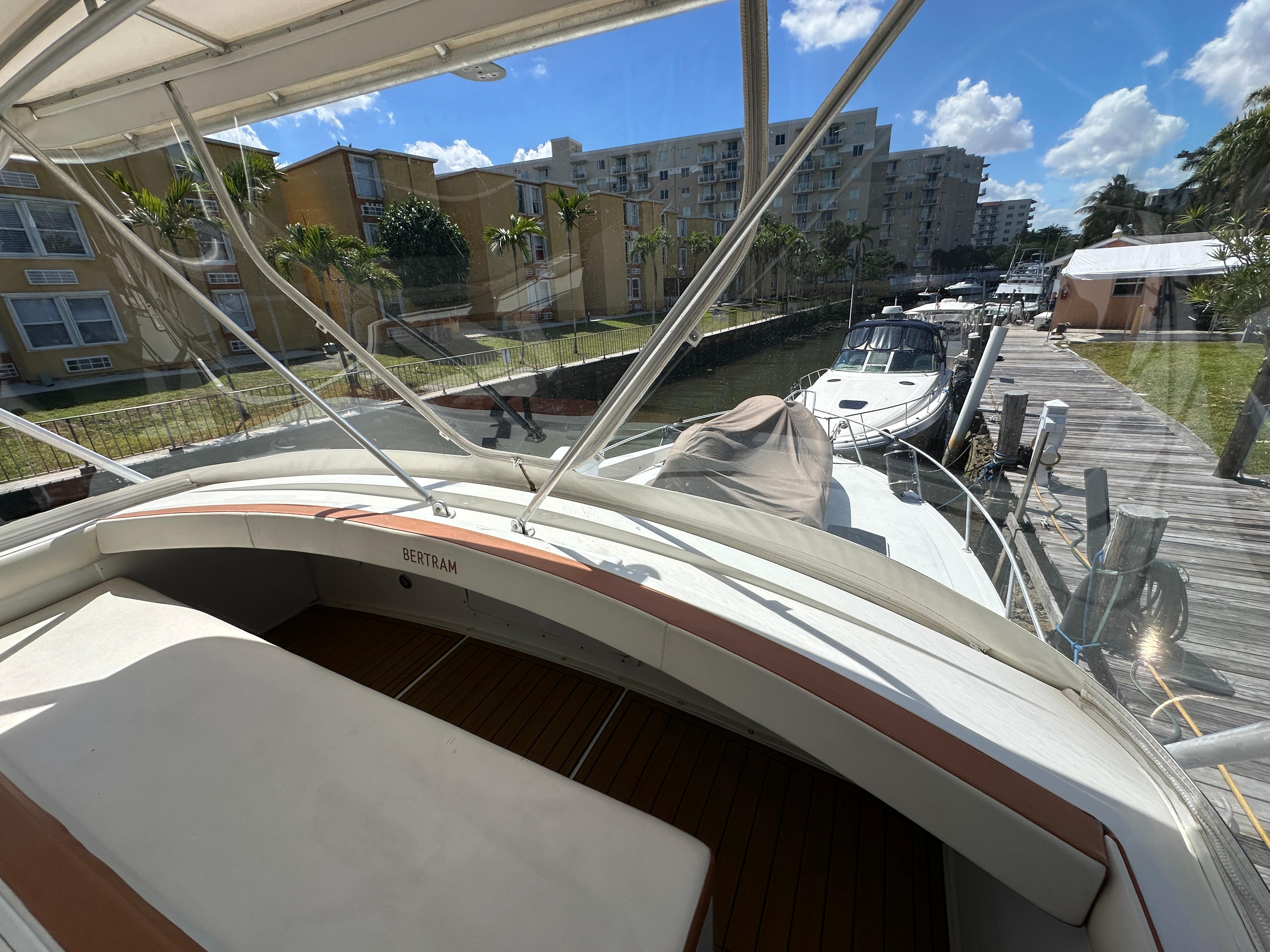 1985 Bertram 46 Convertible yacht docked near waterfront homes under a clear blue sky.