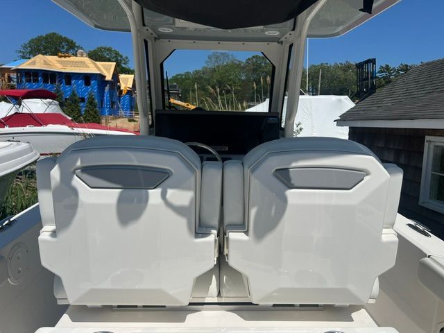 Rear view of two white boat seats with a helm station behind them.
