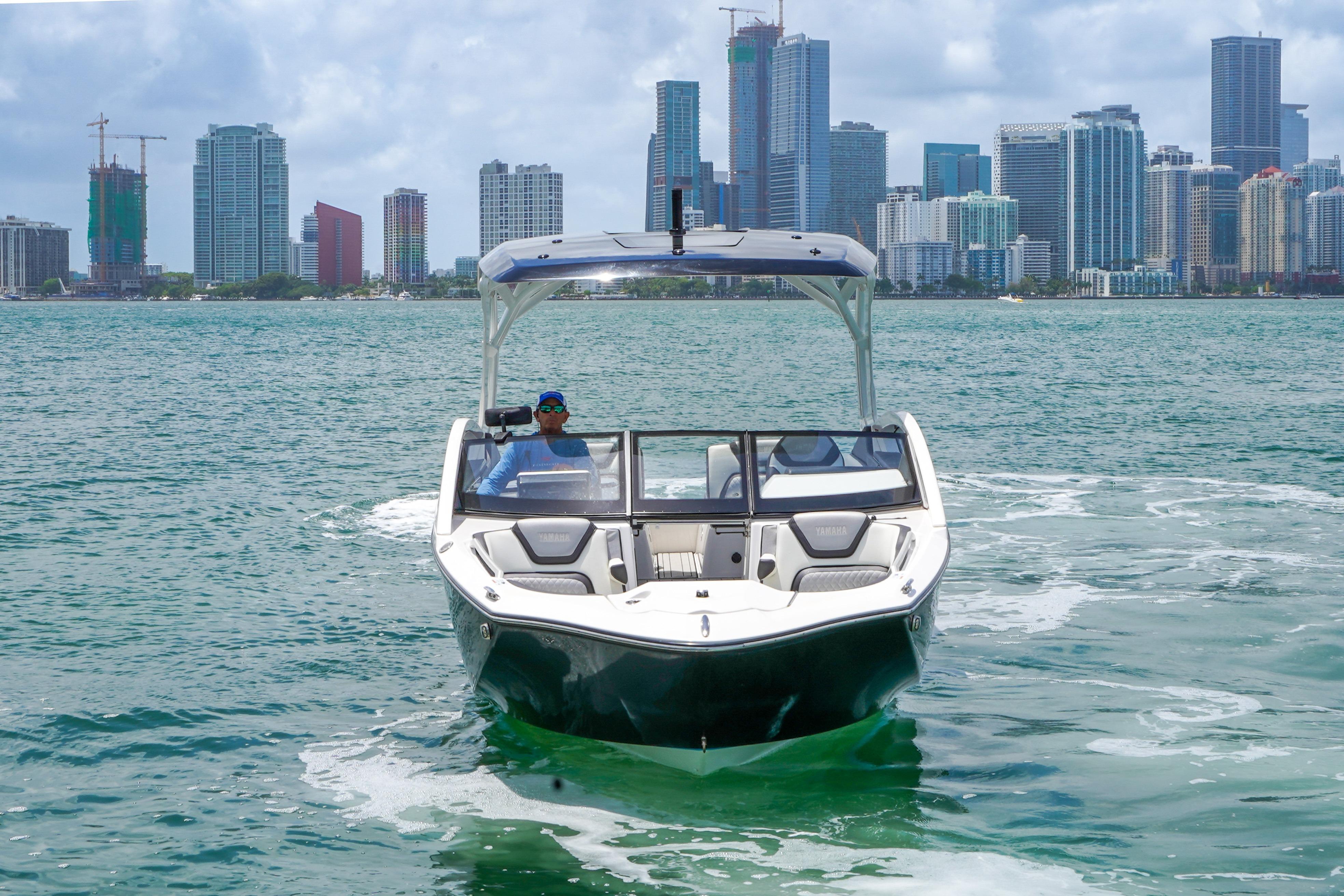 2021 Yamaha Boats 275SD cruising on water with city skyline in background.