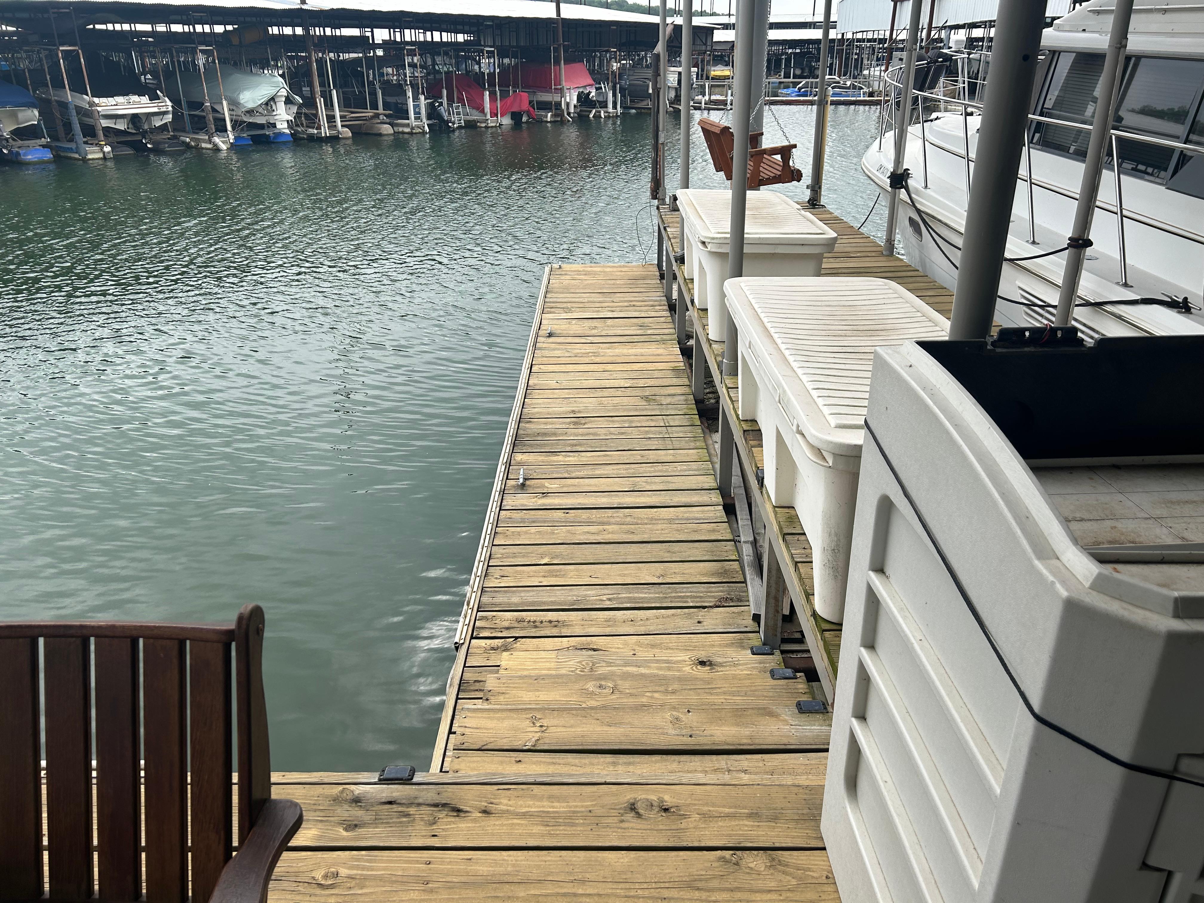 Wooden dock beside Carver 440 Aft Cabin Motor Yacht, 1996, at marina with boats.