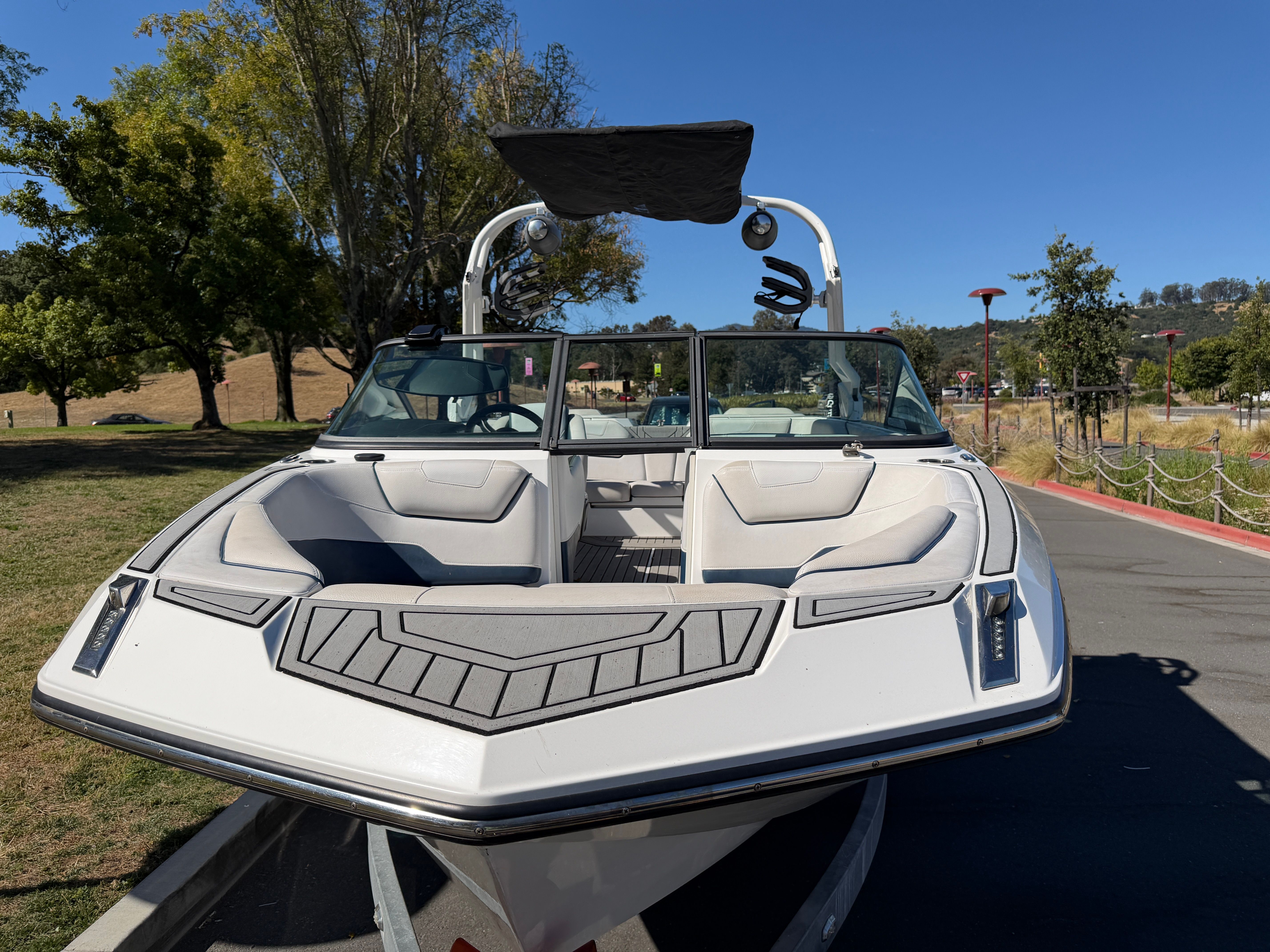 A 2018 Nautique Super Air Nautique GS22 on a trailer, surrounded by trees and a parking area.
