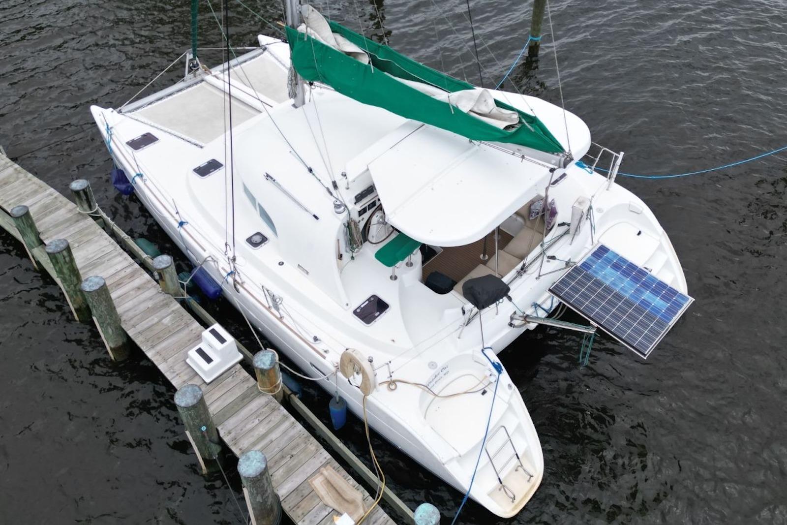 Aerial view of a 2004 Lagoon 380 catamaran docked, featuring solar panels and green sail.