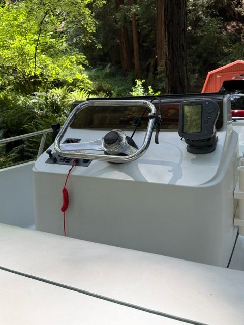 The cockpit of a Boston Whaler 13' jet boat with steering wheel and controls.