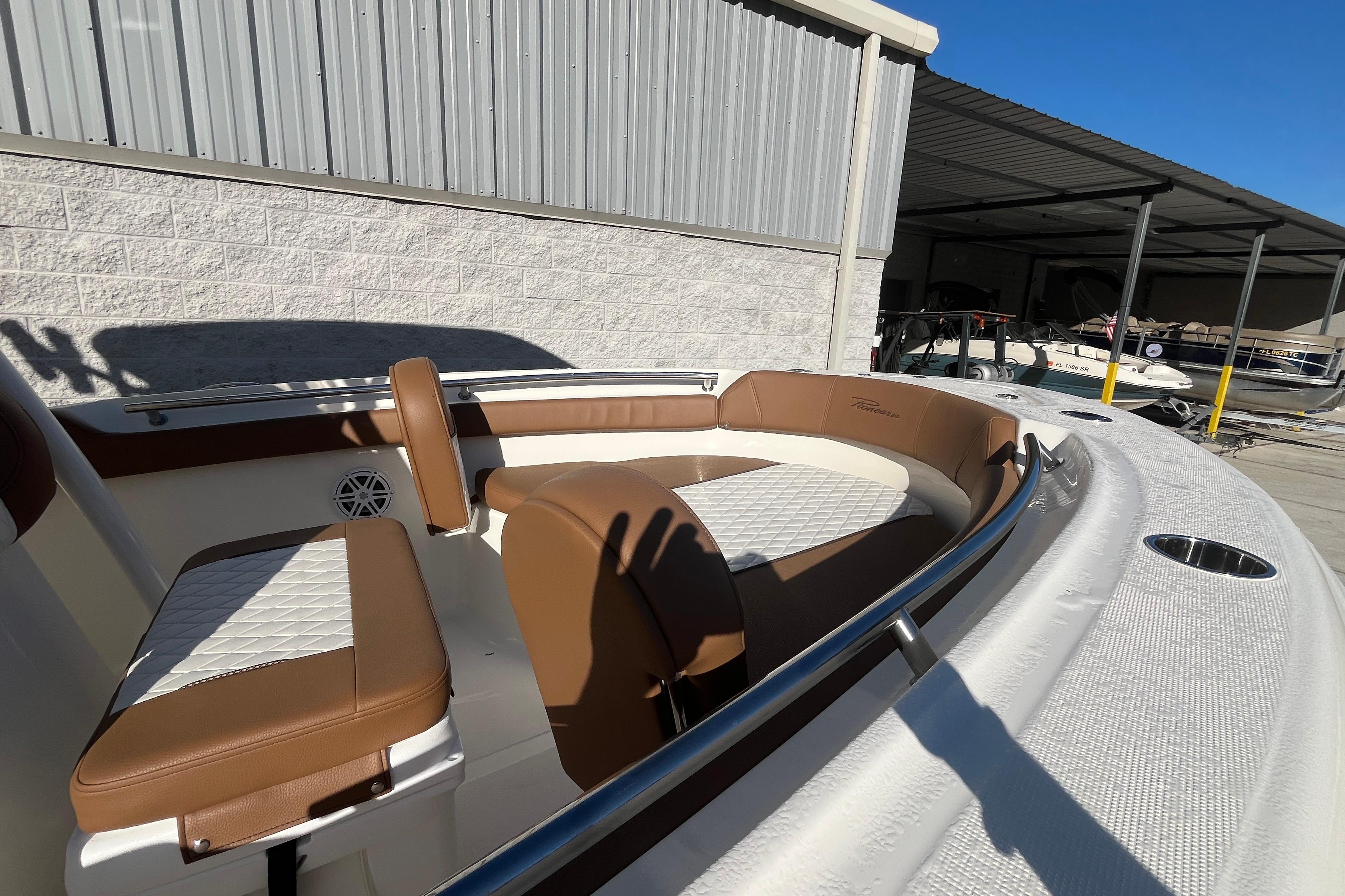 2026 Pioneer 202 Sportfish boat interior with brown and white seating, docked in a marina.