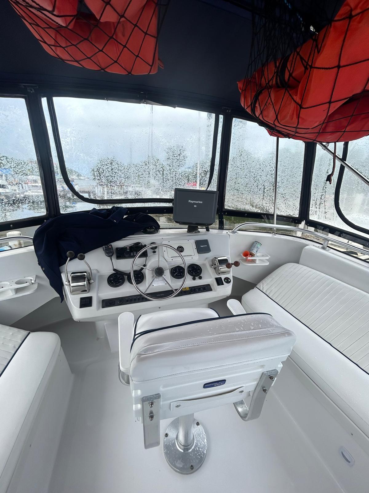 1999 Mainship 350 Trawler helm with steering wheel, navigation equipment, and seating.
