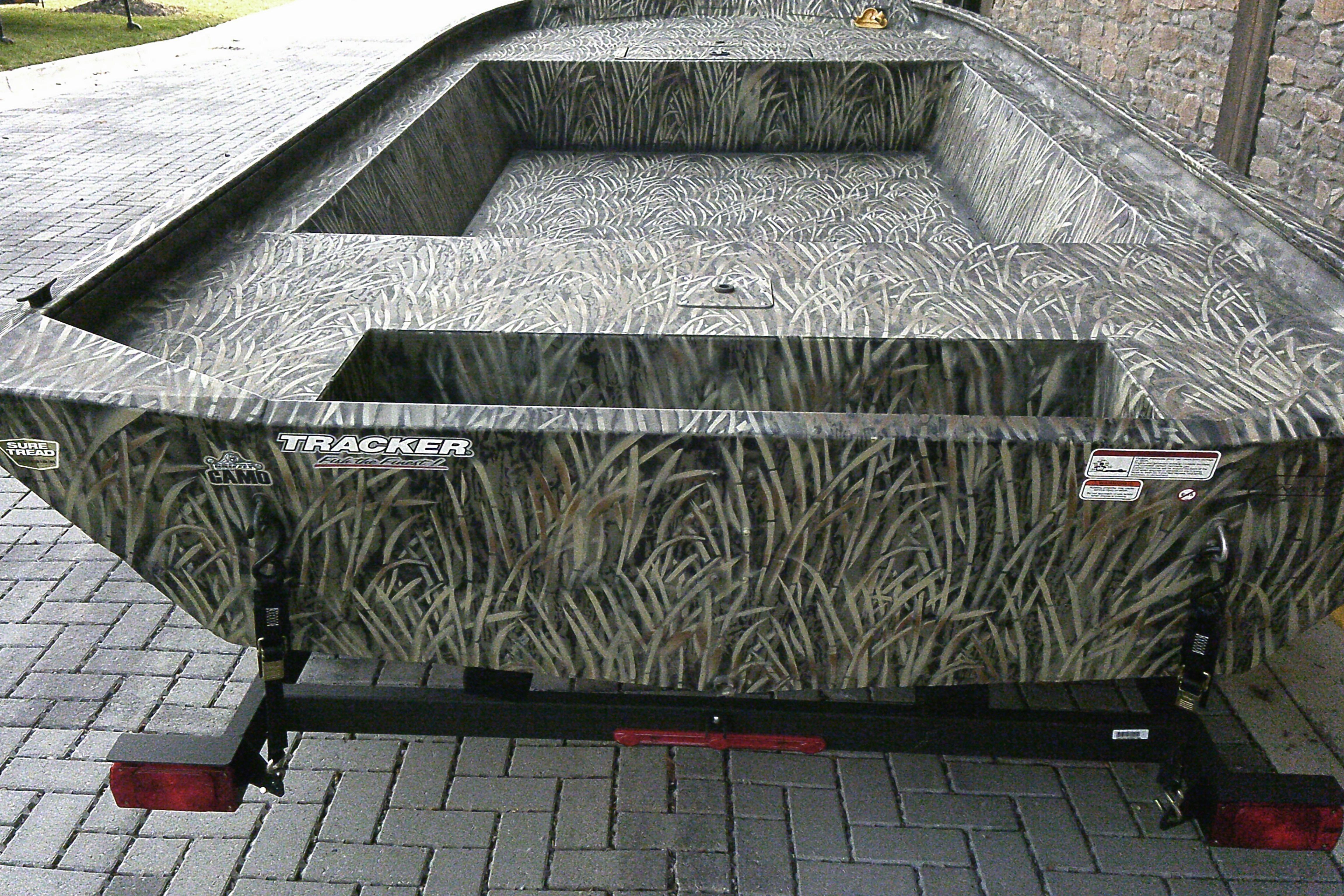 2026 Tracker Grizzly 1860 Utility boat with camo design on a brick driveway.