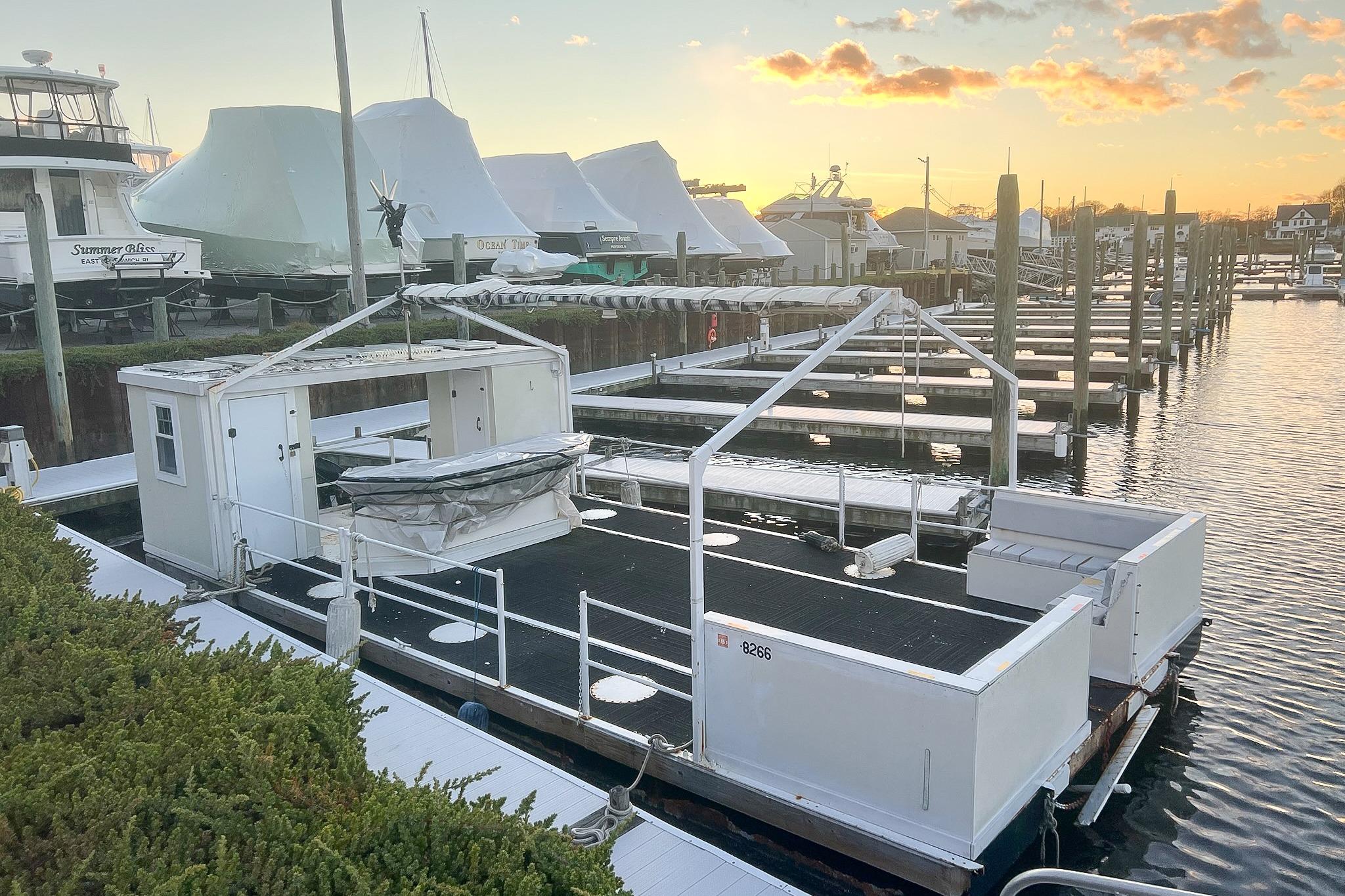 Custom MK1 2022 houseboat docked at marina during sunset, surrounded by other boats.