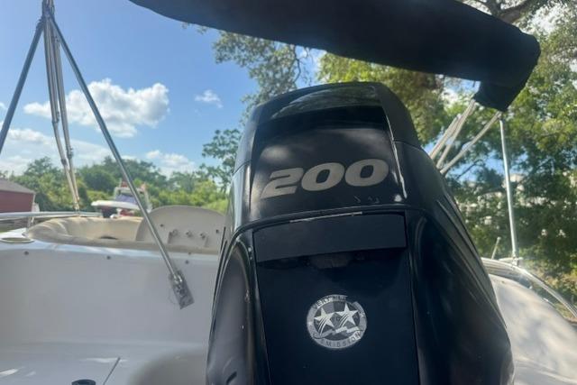 1999 Hurricane SunDeck Sport 201 OB boat with 200 HP engine, outdoors under blue sky.