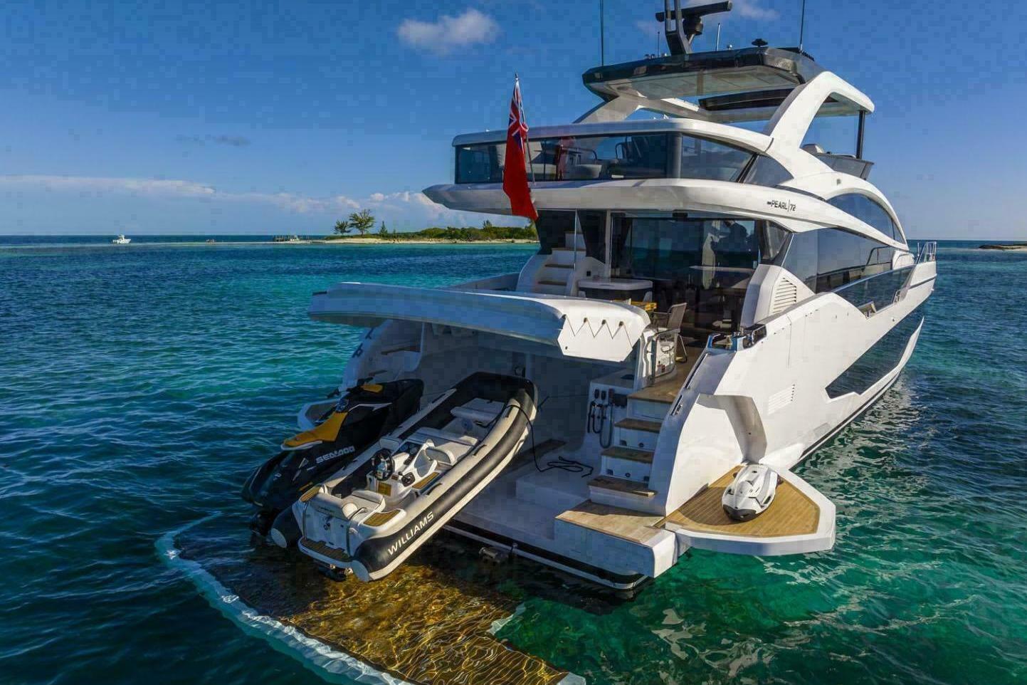 Luxurious 2023 Pearl 72 yacht with jet skis, anchored in clear blue waters.