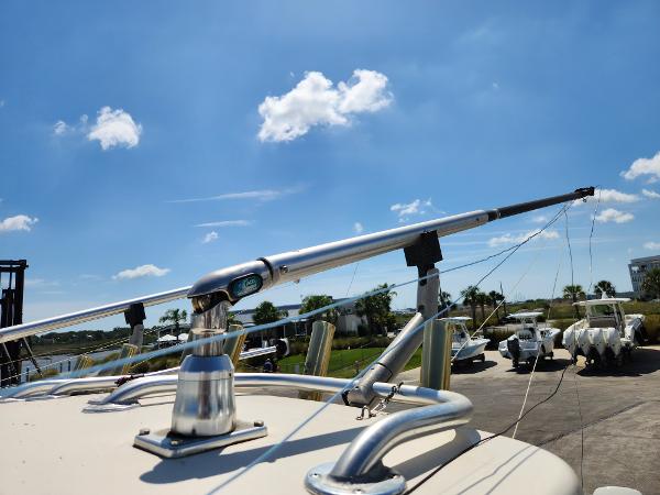 A boat with stainless steel railings and fishing rod holders under a blue sky.