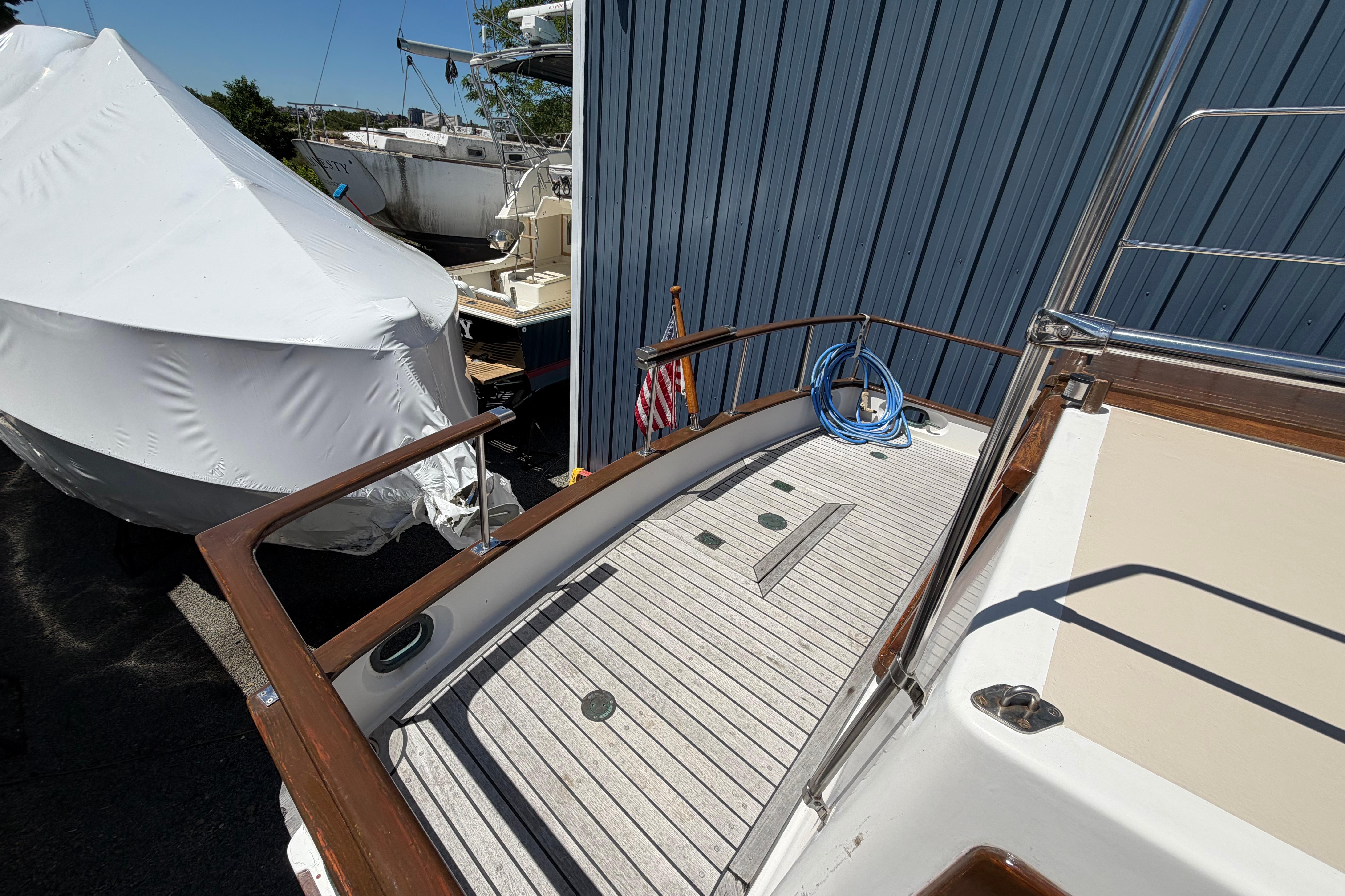 1987 Marine Trader 36 yacht deck with wooden railings and coiled blue hose.