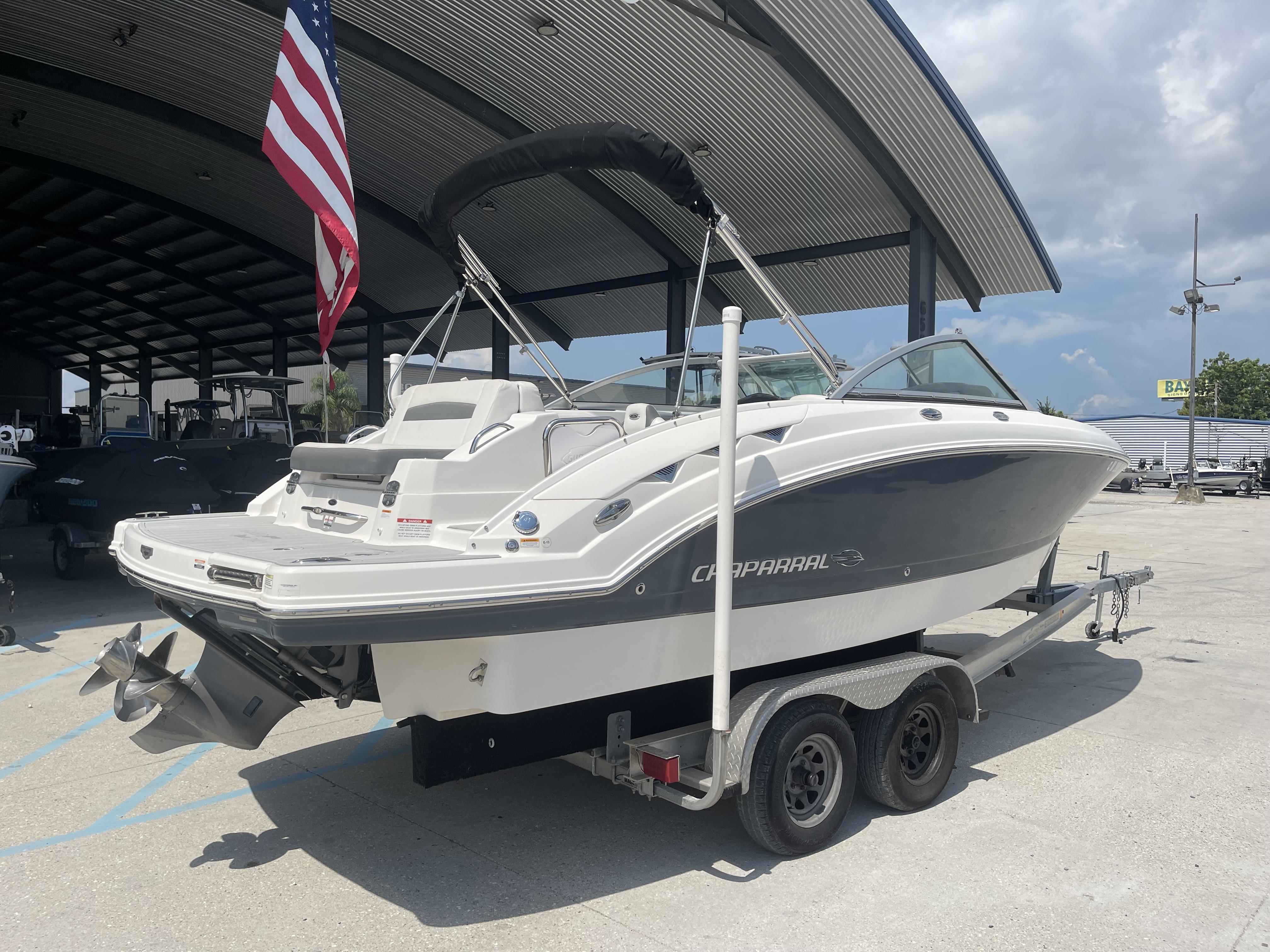 2014 Chaparral Sunesta 224 boat on trailer, parked under a canopy with an American flag.