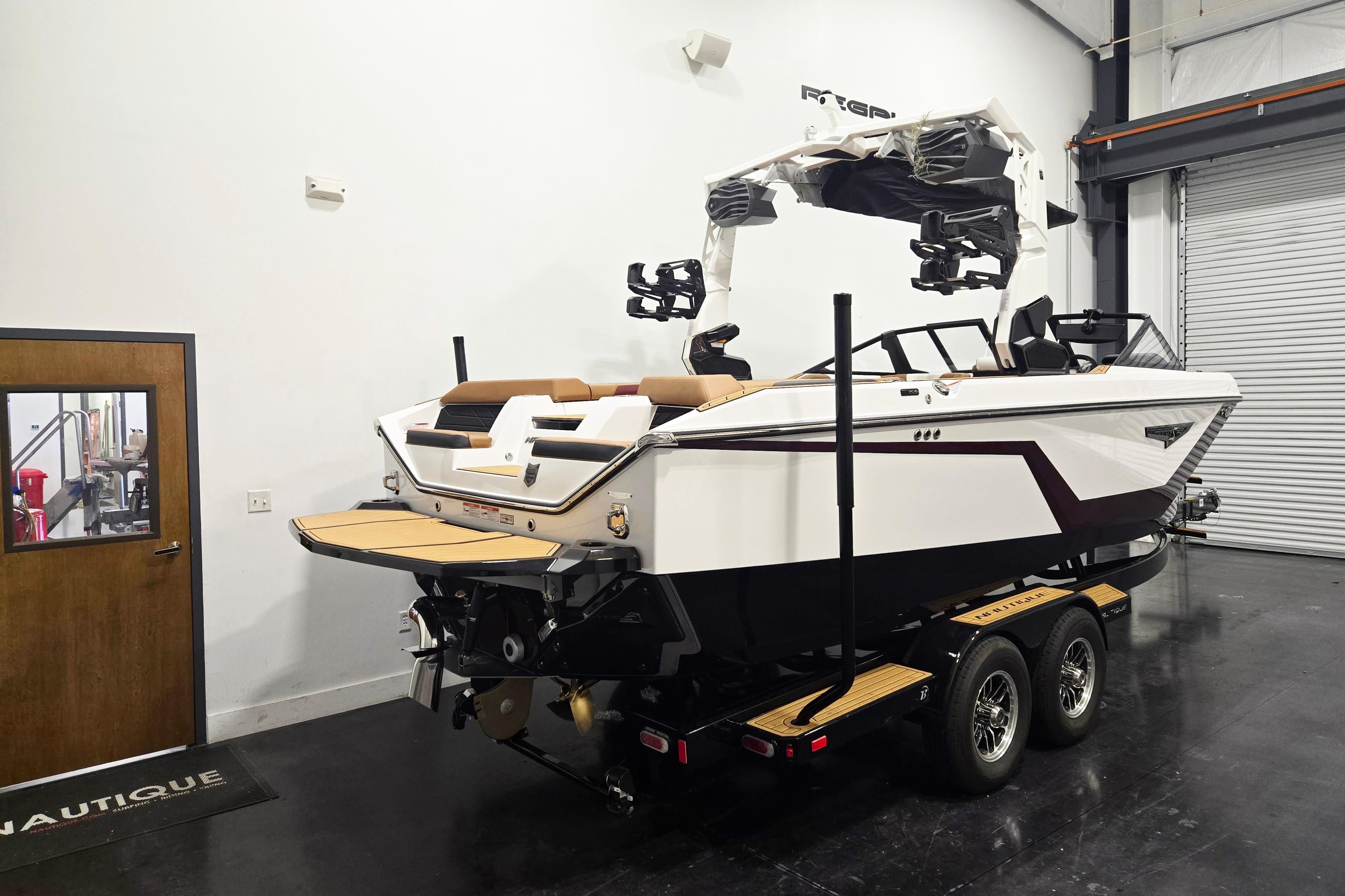 2026 Nautique Super Air Nautique S23 boat in showroom, on trailer, rear view.