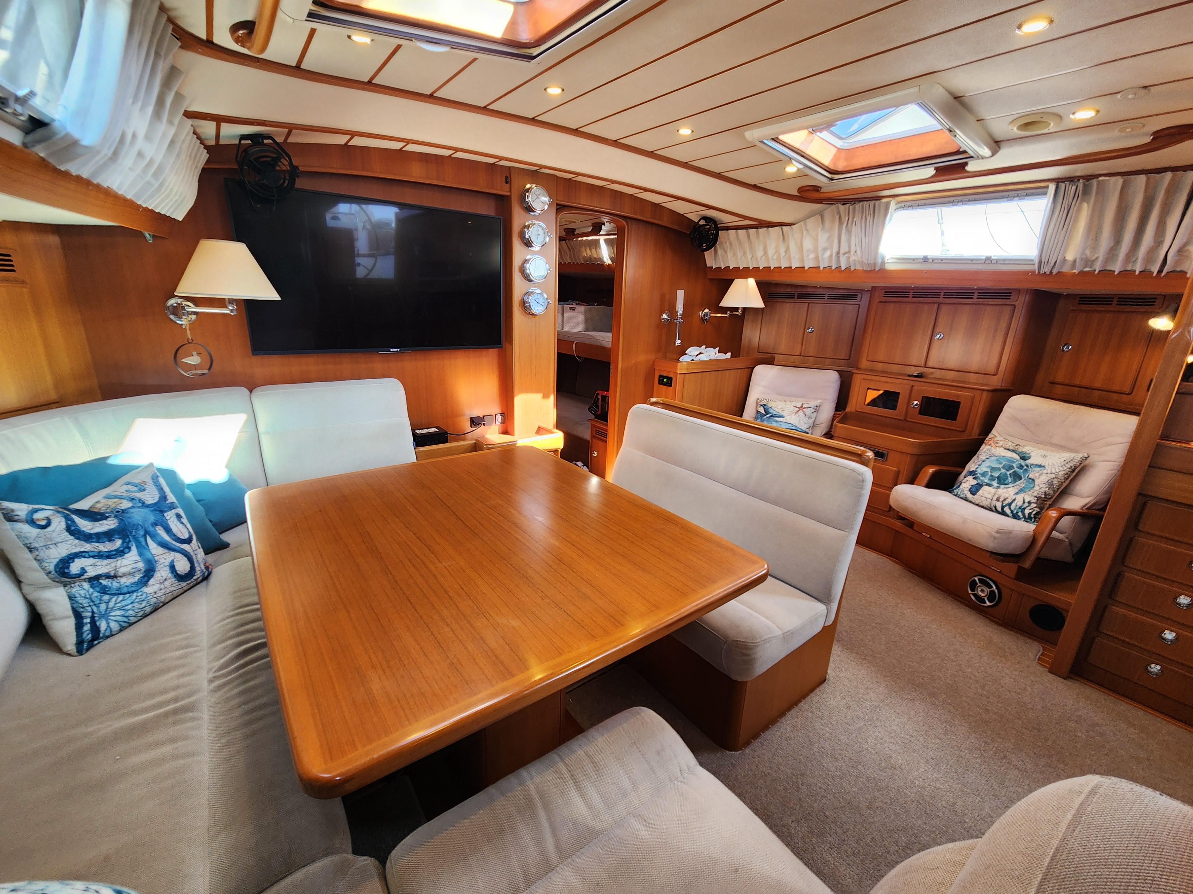 Luxurious interior of a 2008 Hallberg-Rassy 62 yacht with elegant wood finishes and cozy seating.