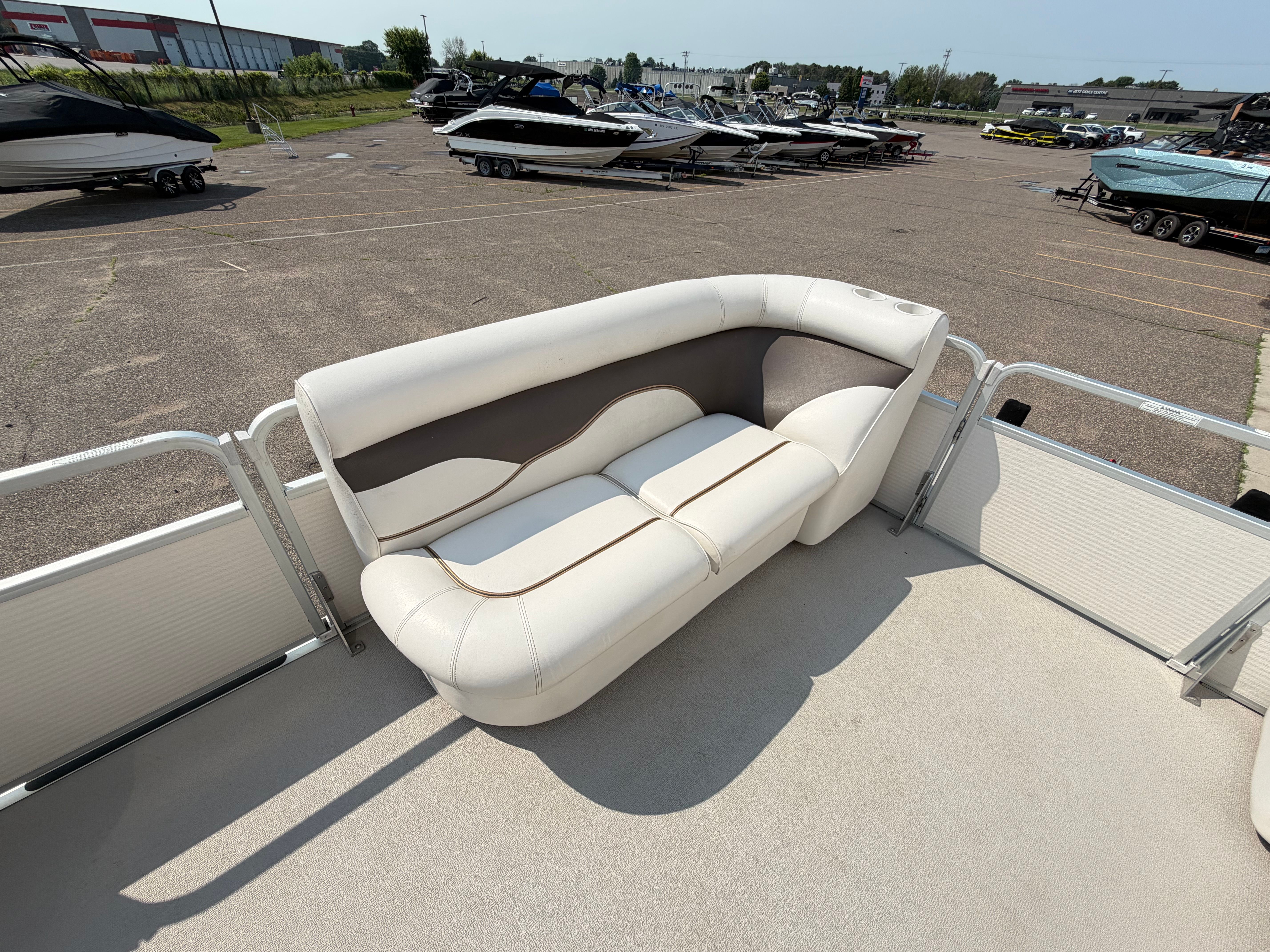 The image shows a white seating area on a pontoon boat parked in a lot.