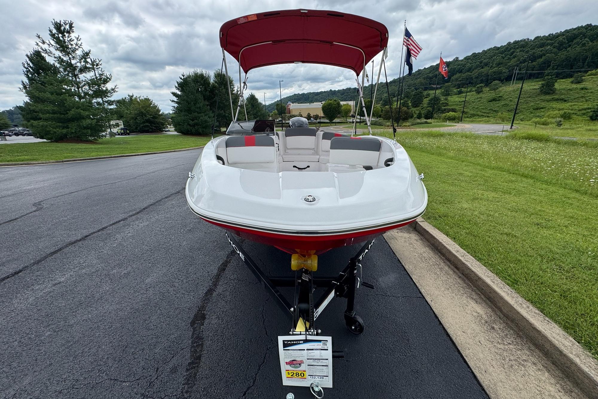 2026 Tahoe T16 boat with red canopy on a trailer, parked on a paved road.