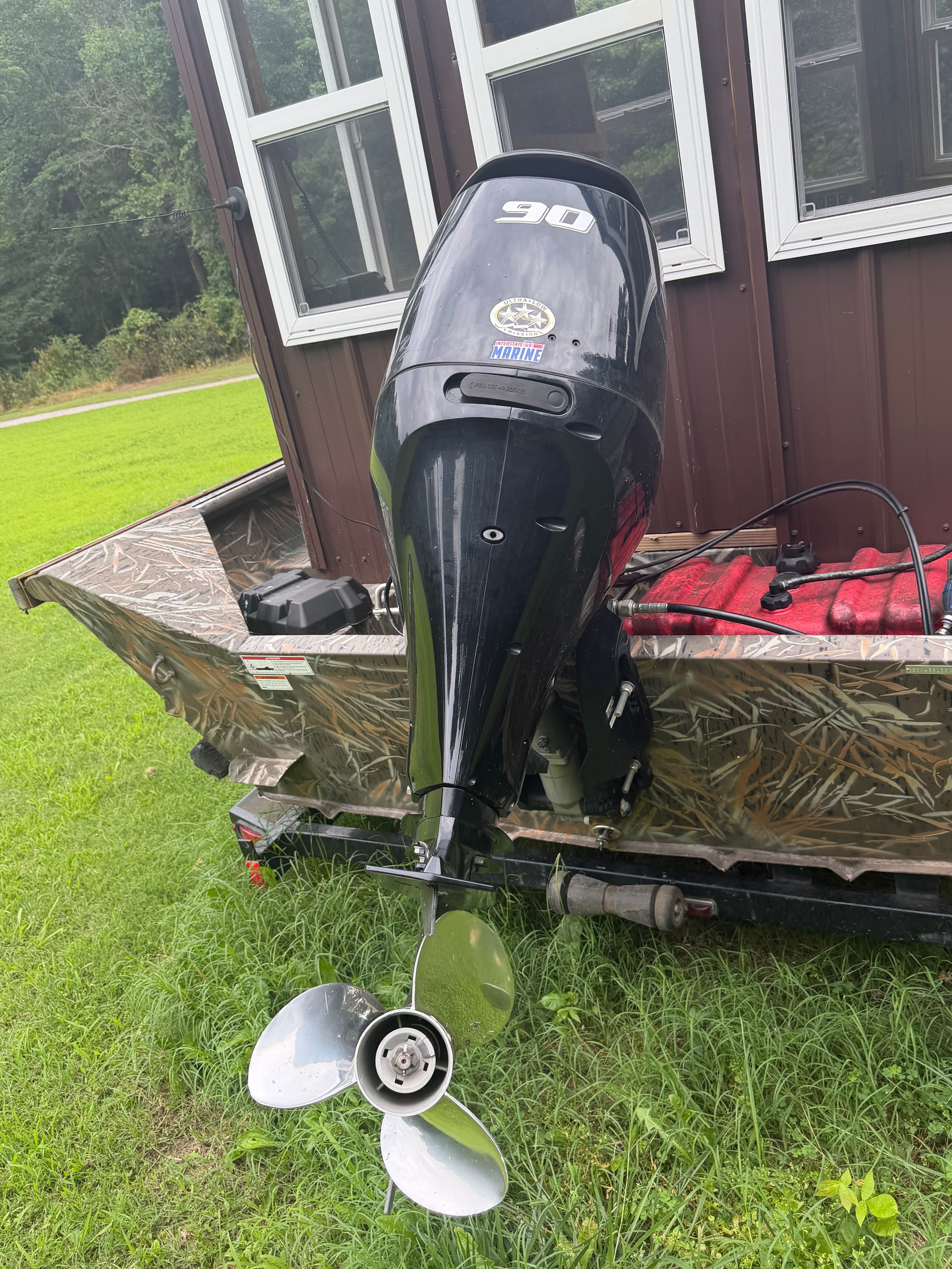 An outboard motor on a boat, sitting on a trailer on a grassy area.
