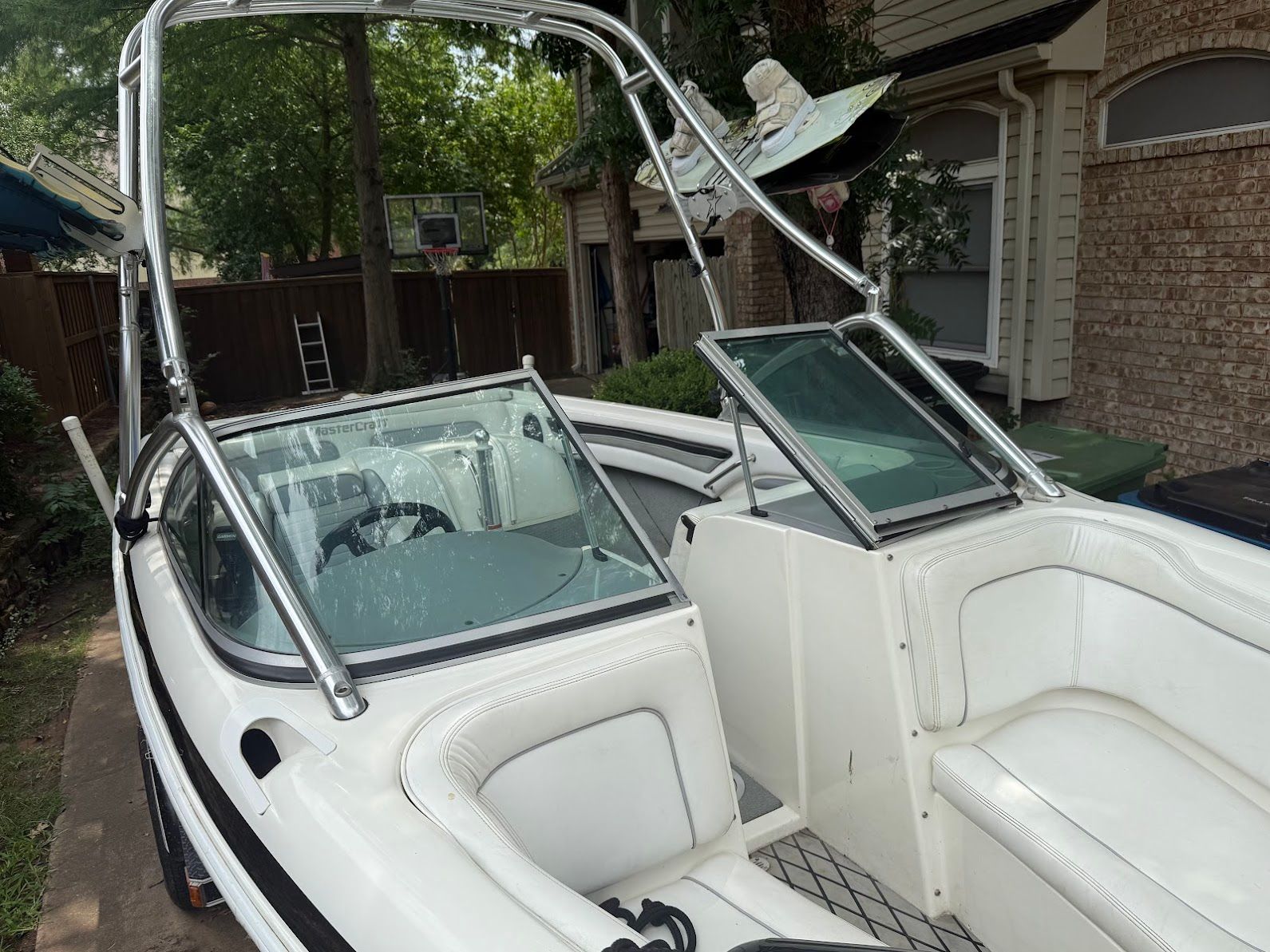 A 1999 MasterCraft Prostar 205 with white interior and a tower, parked in a driveway.