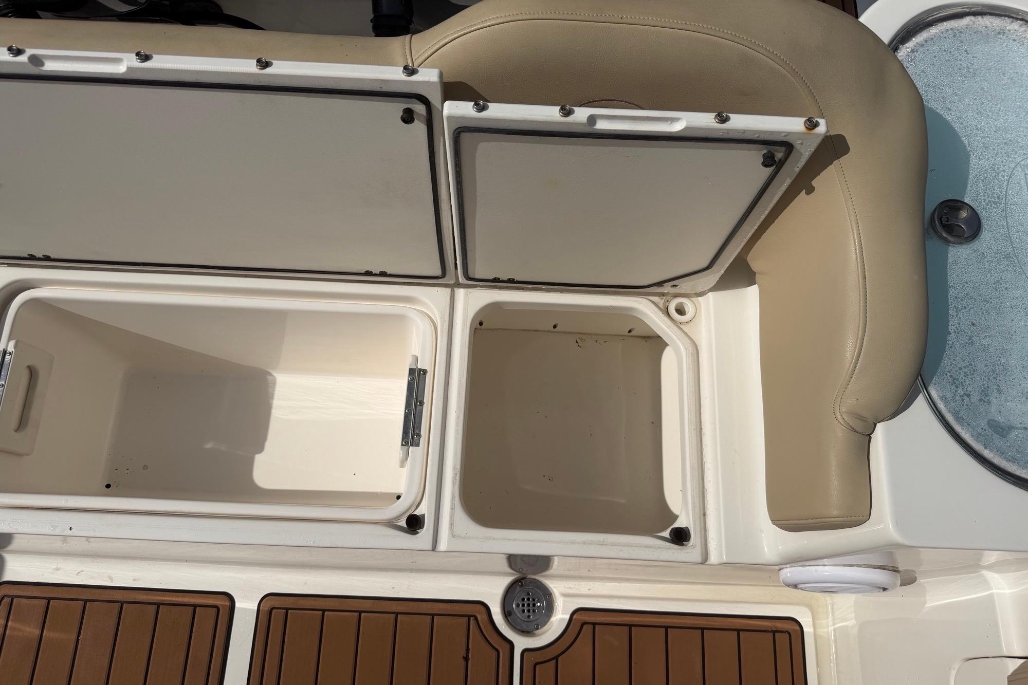 Open storage compartments on a 2019 Key West 263 FS boat, featuring beige seating.